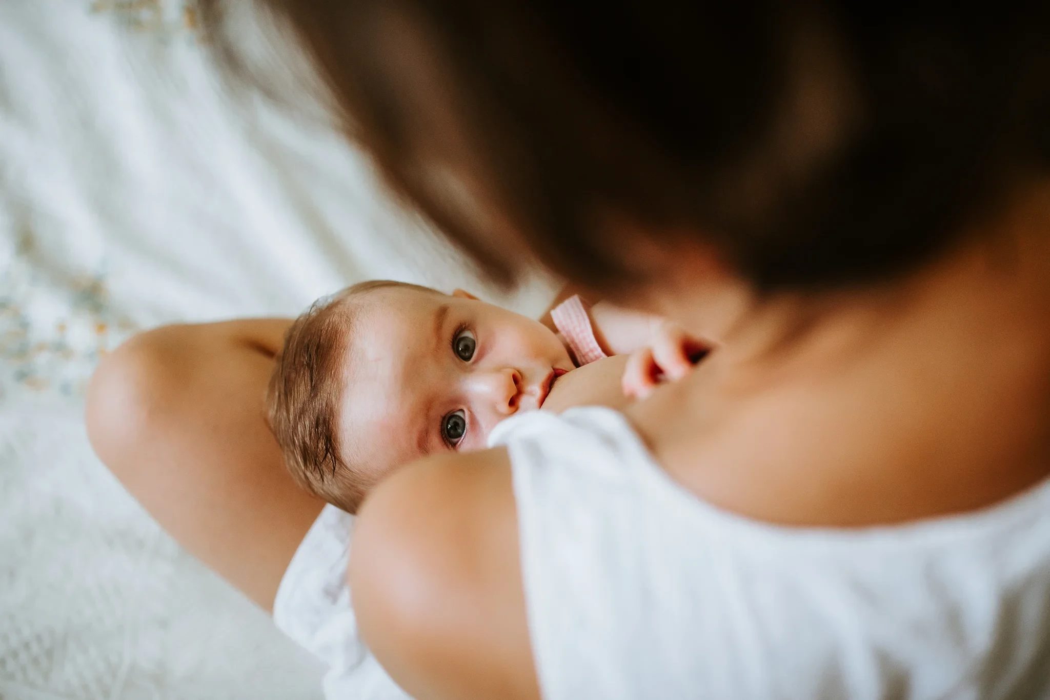 Baby looks over a woman’s shoulder toward the camera