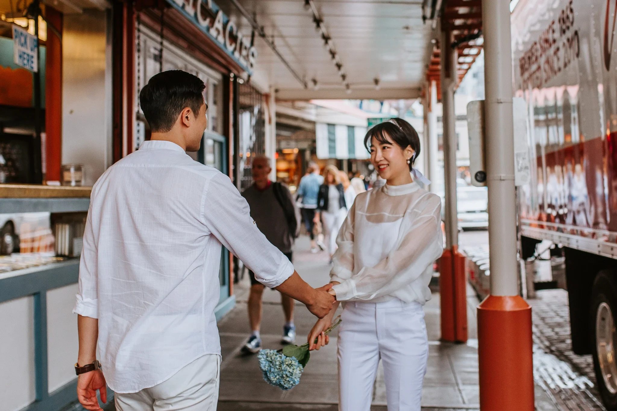 Two adults hold hands beneath a covered city walkway