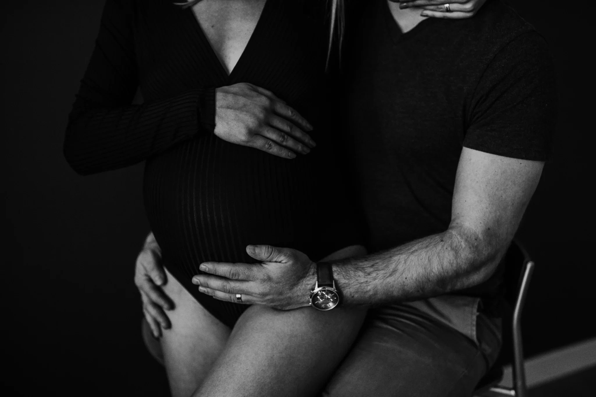 Close-up of two adults in dark clothing with their hands resting together