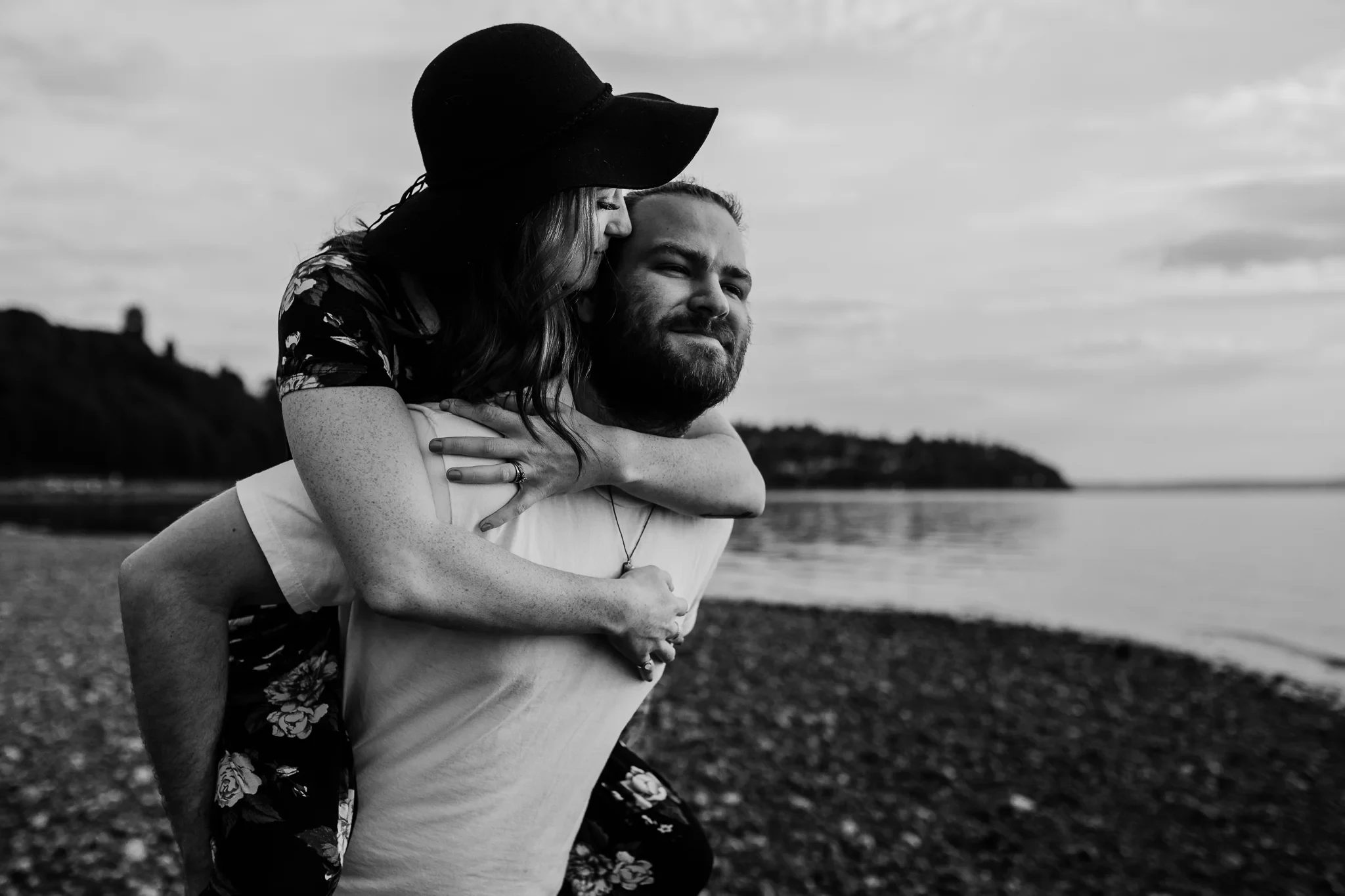 Black-and-white photograph of a woman riding on a man’s back at the beach