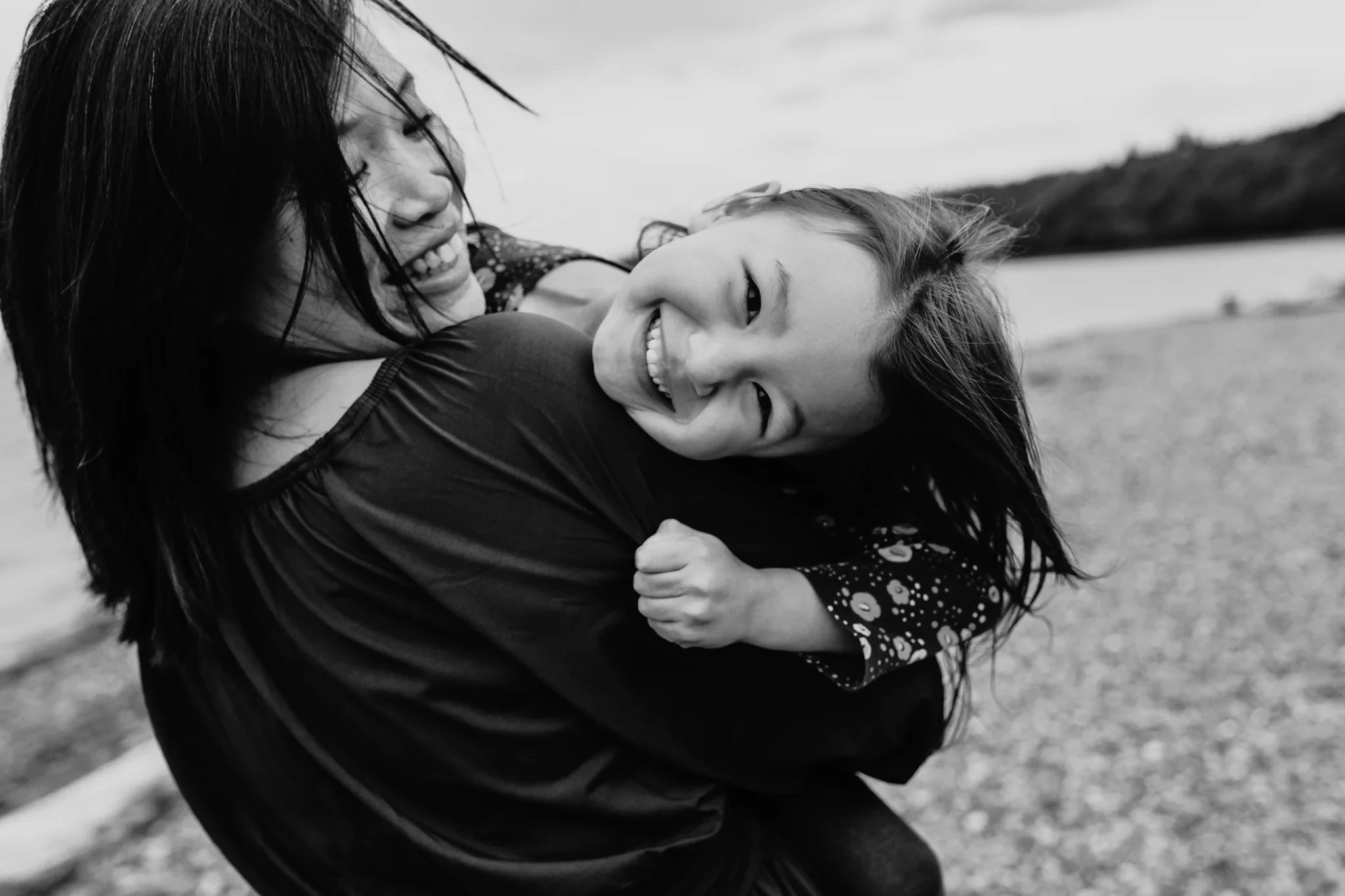Black-and-white photograph of a woman lifting a laughing child sideways