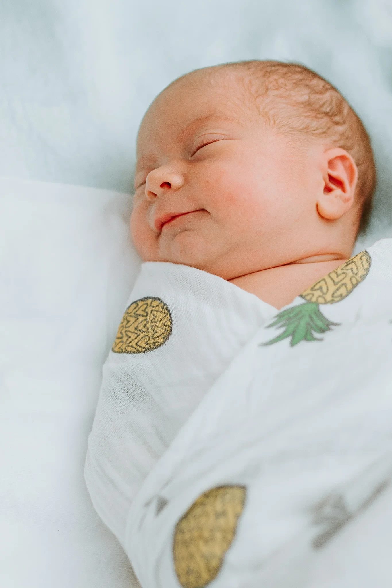 Close-up of a sleeping baby in a pineapple-print wrap