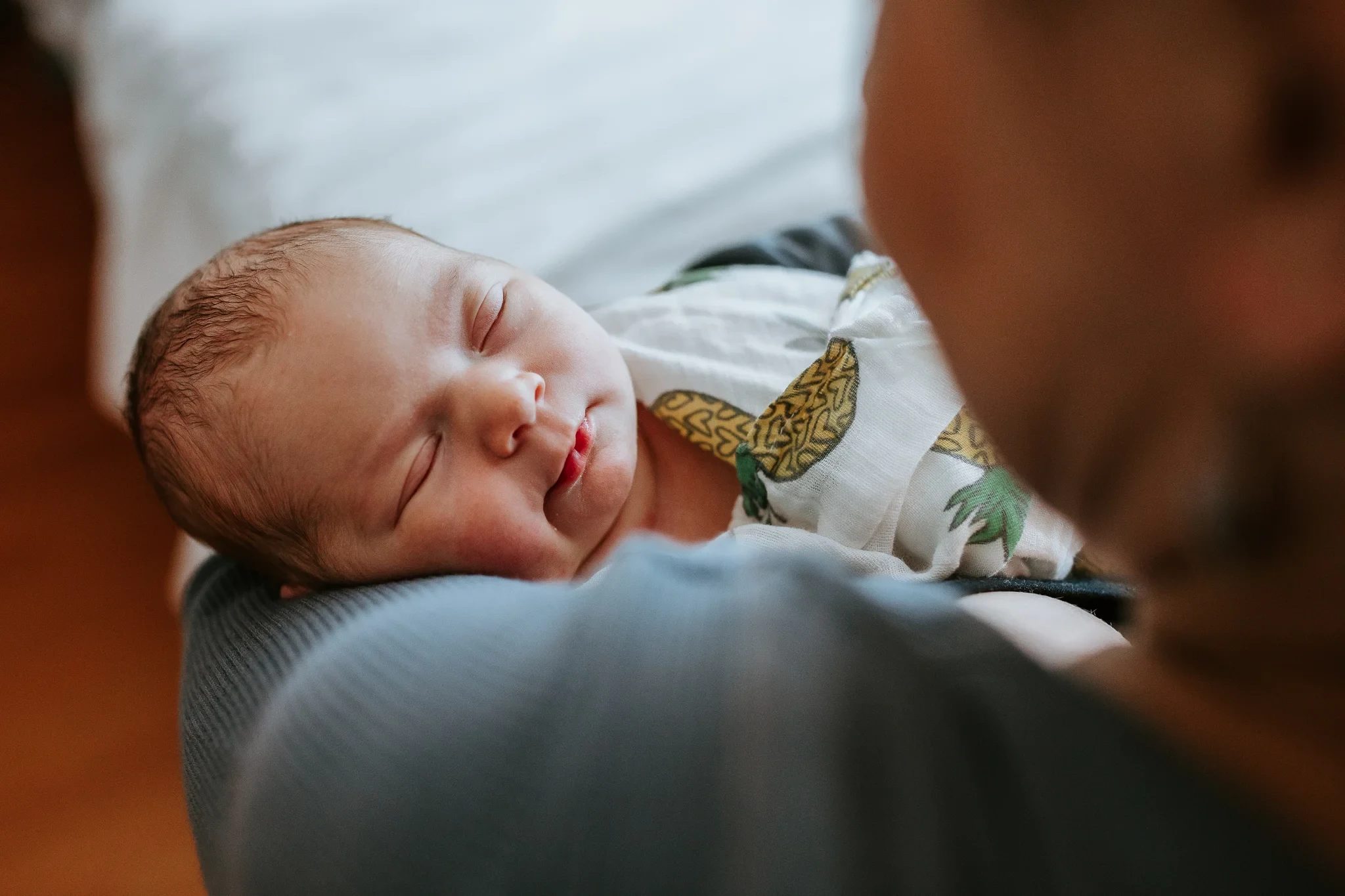 Baby sleeps on an adult’s forearm in a hospital room