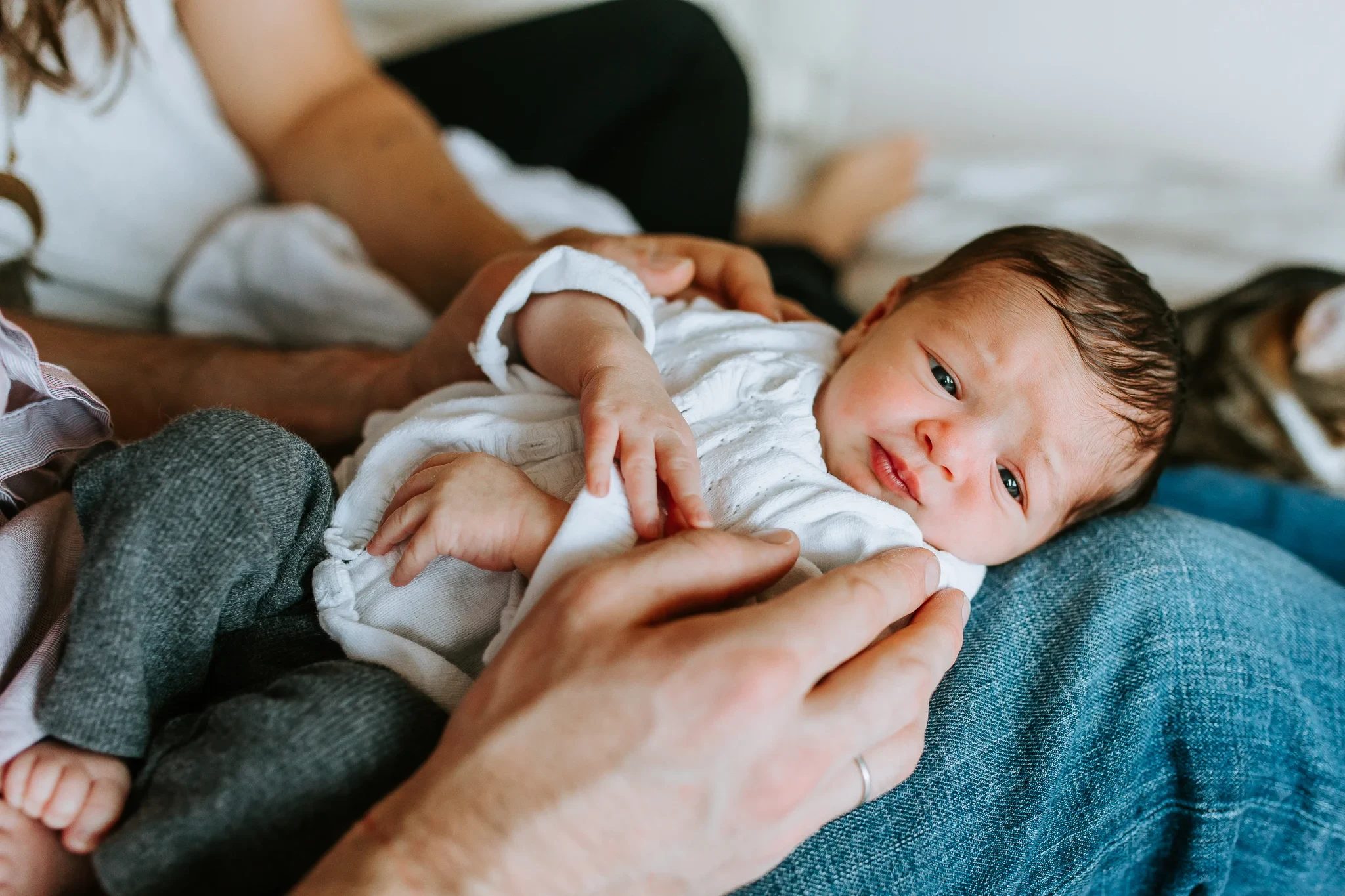Baby rests across an adult’s lap while a hand gently holds tiny fingers