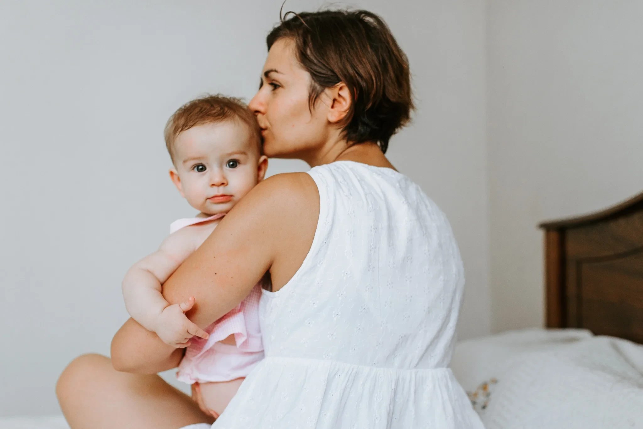 Woman in a white top holds a baby against her shoulder