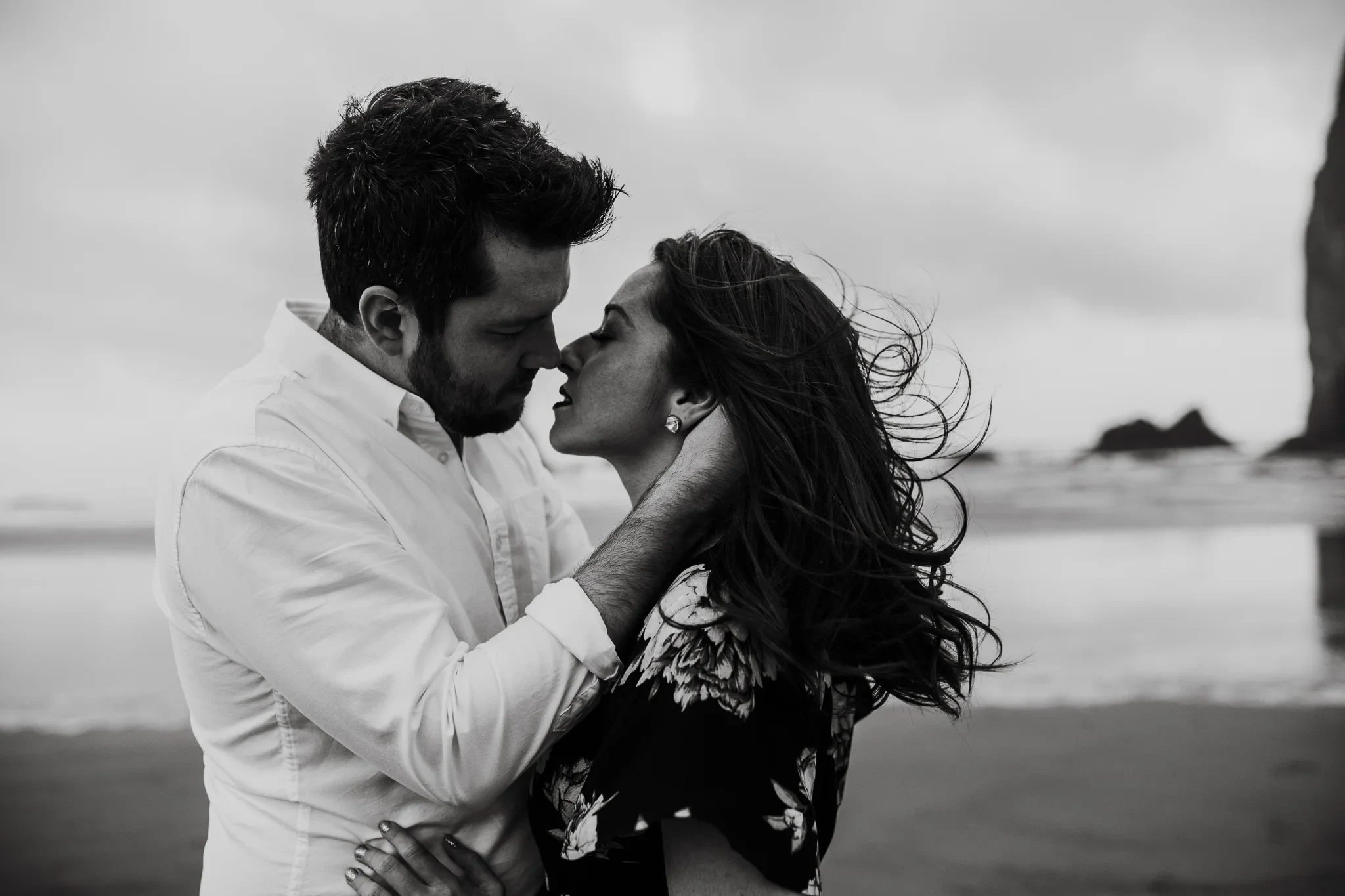 Black-and-white photograph of two adults kissing on a beach