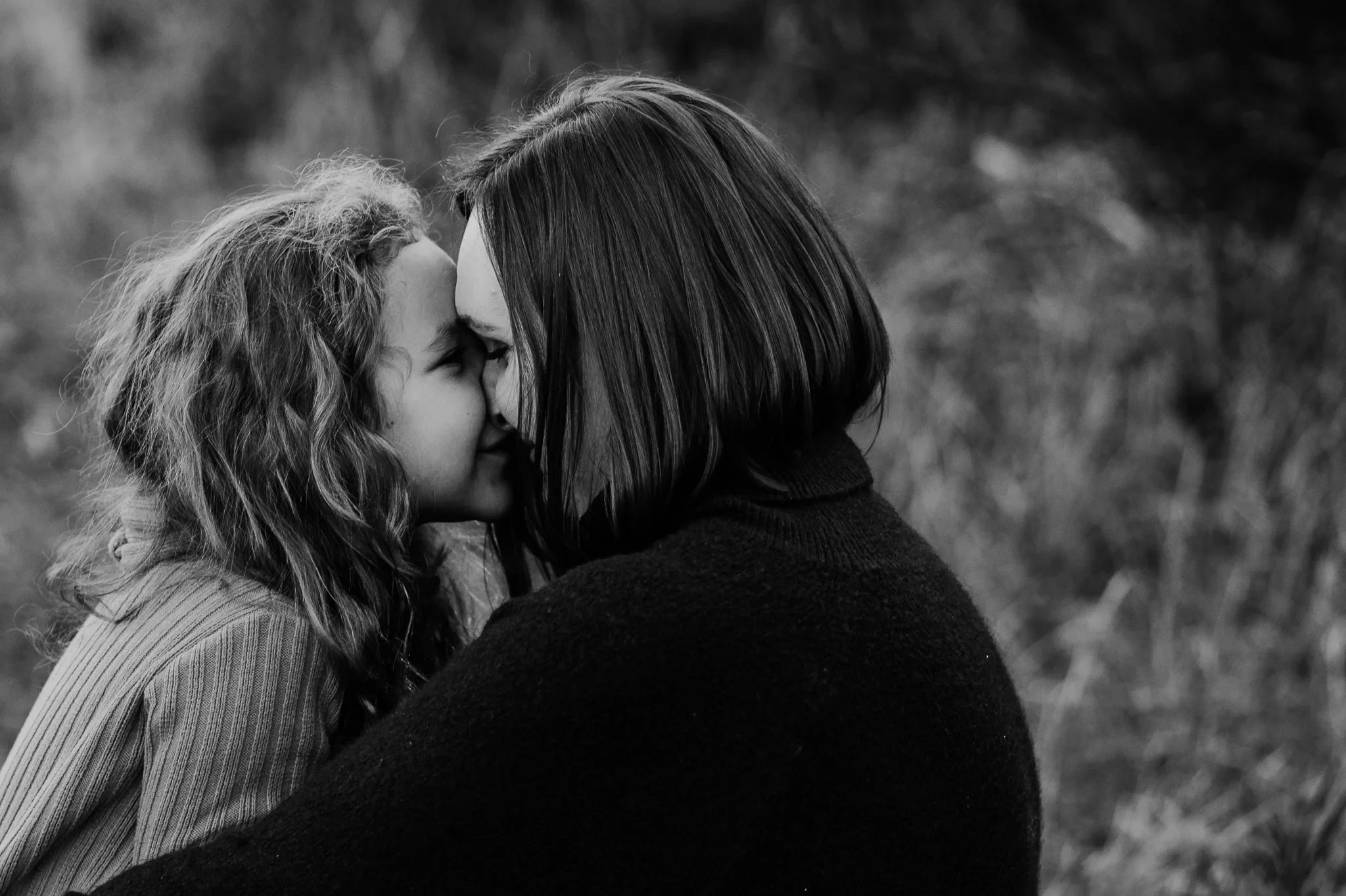 Black-and-white close-up of a child touching noses with a woman