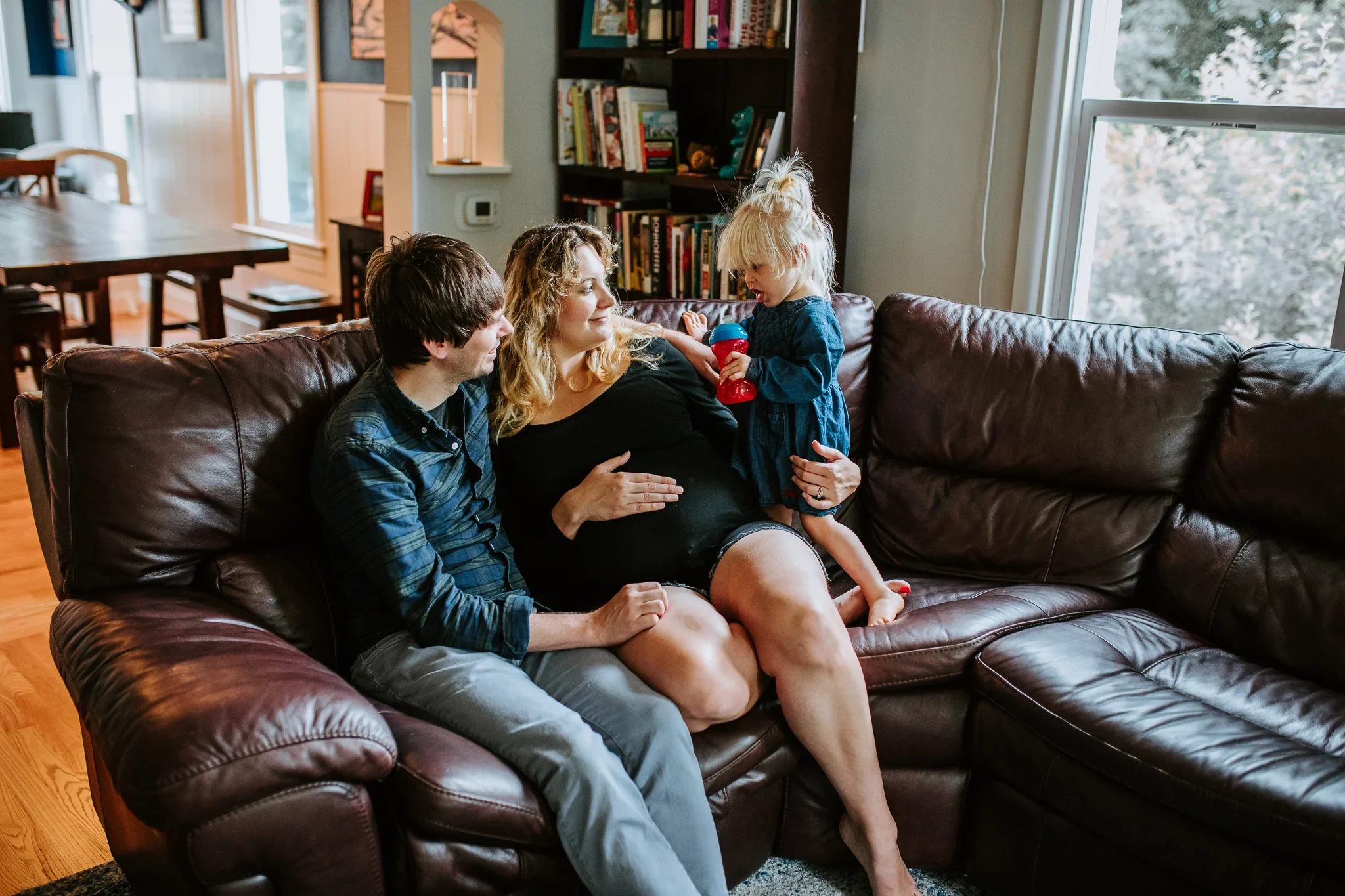 Woman and two children relax together on a leather sofa