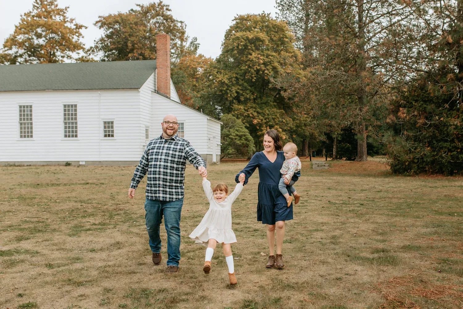 Family walks together across a lawn in front of a white building