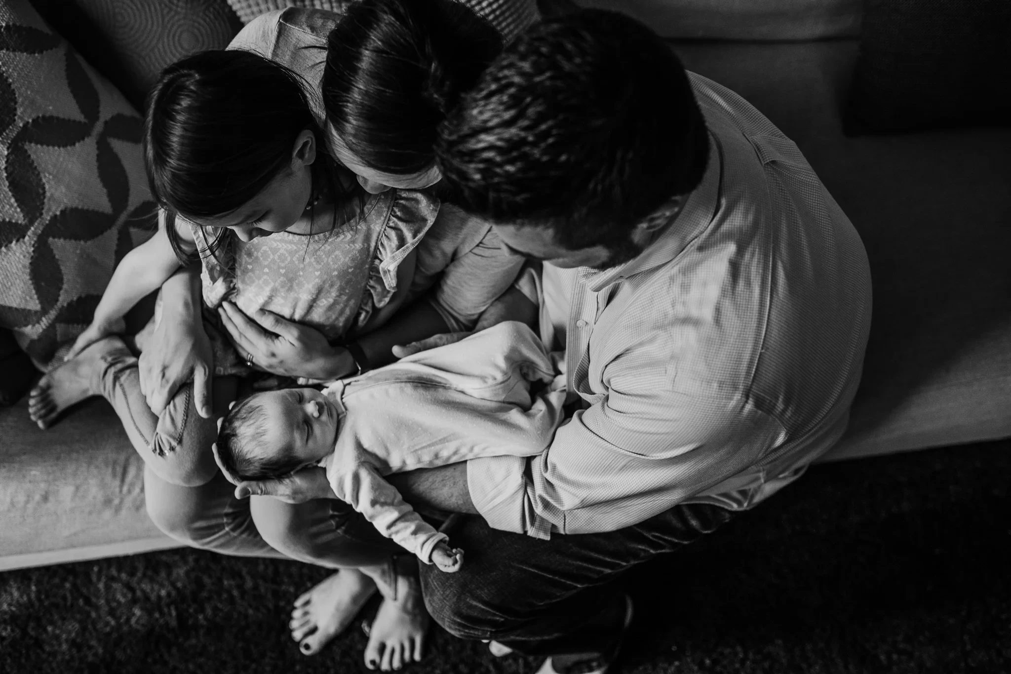 Black-and-white overhead view of two adults holding a baby