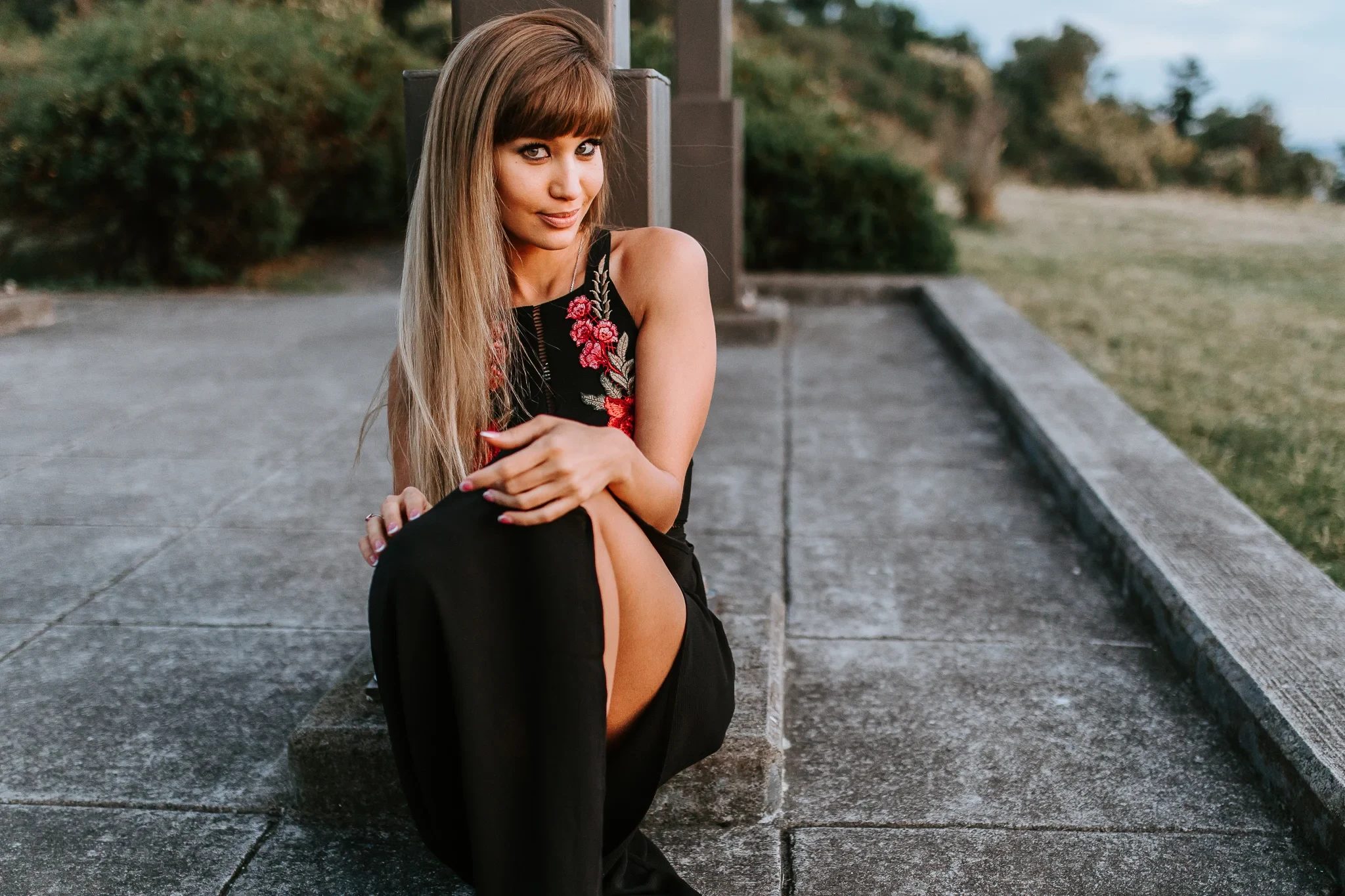 Woman in a black dress sits on a rooftop terrace