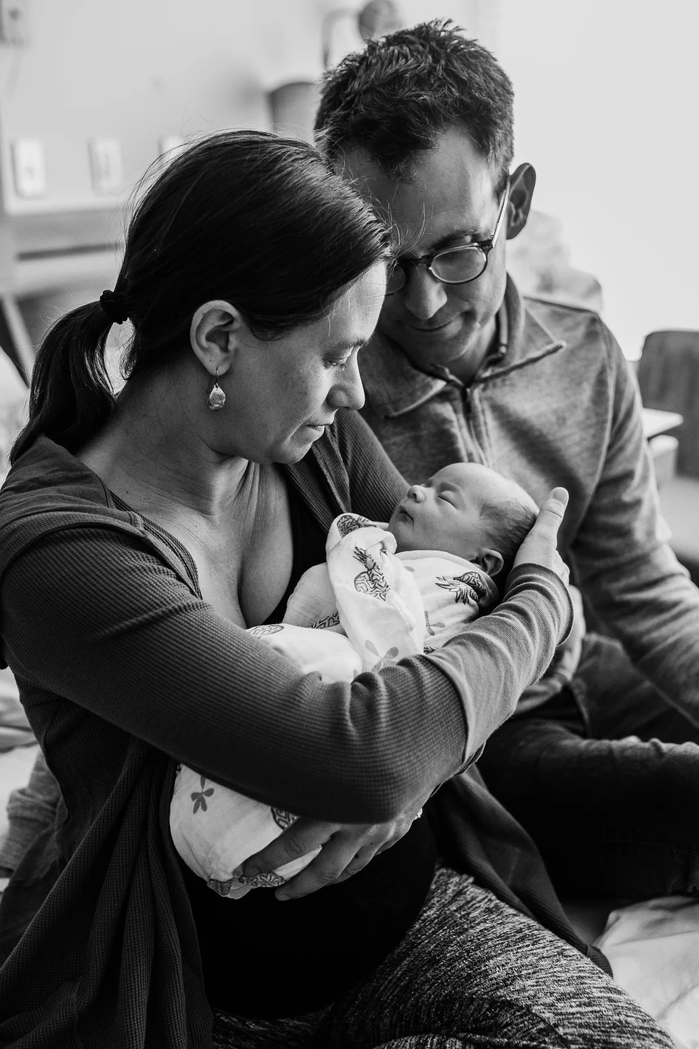 Black-and-white photograph of two adults cradling a baby together