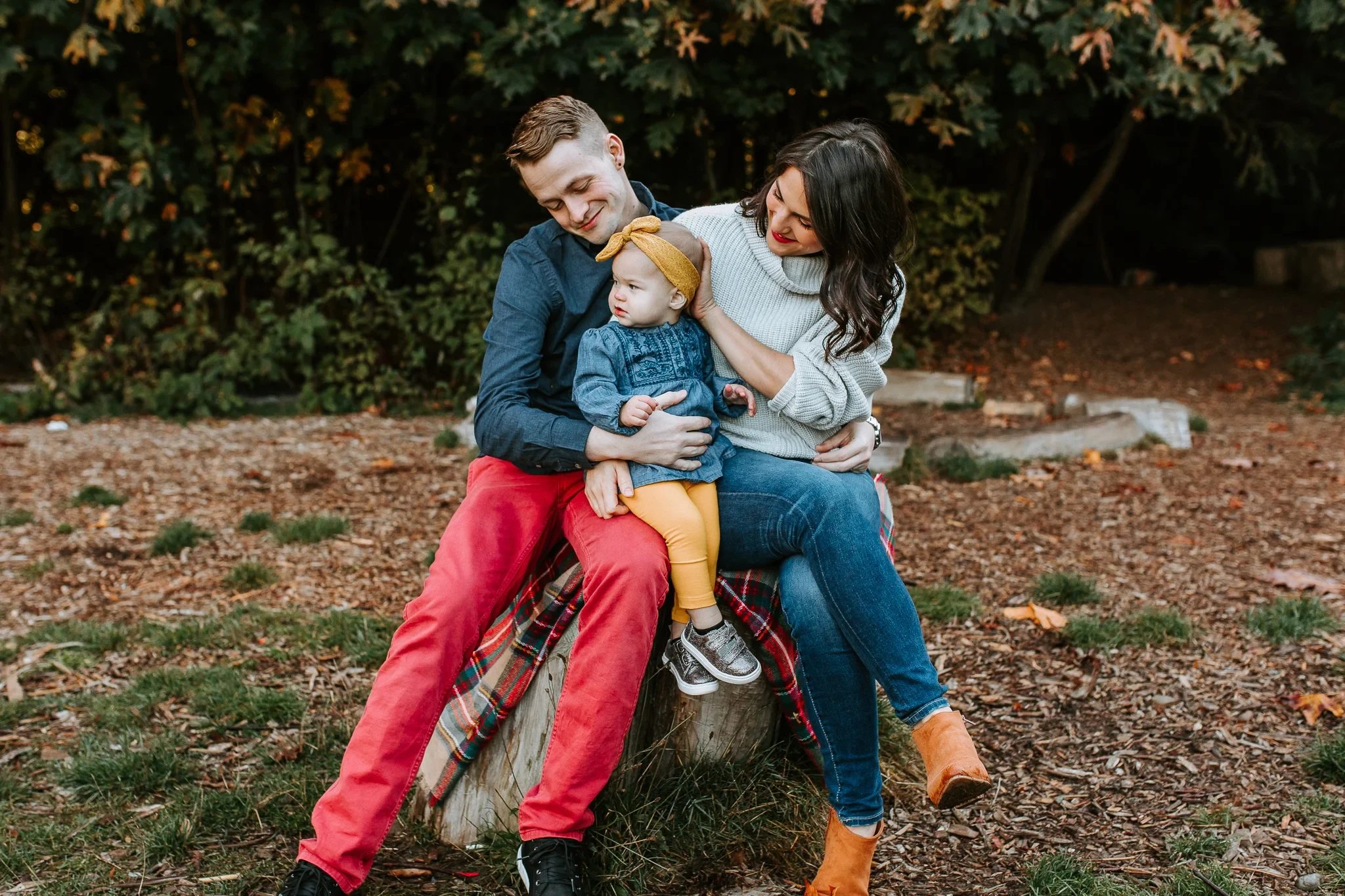Two adults and a toddler sit close together on an outdoor bench