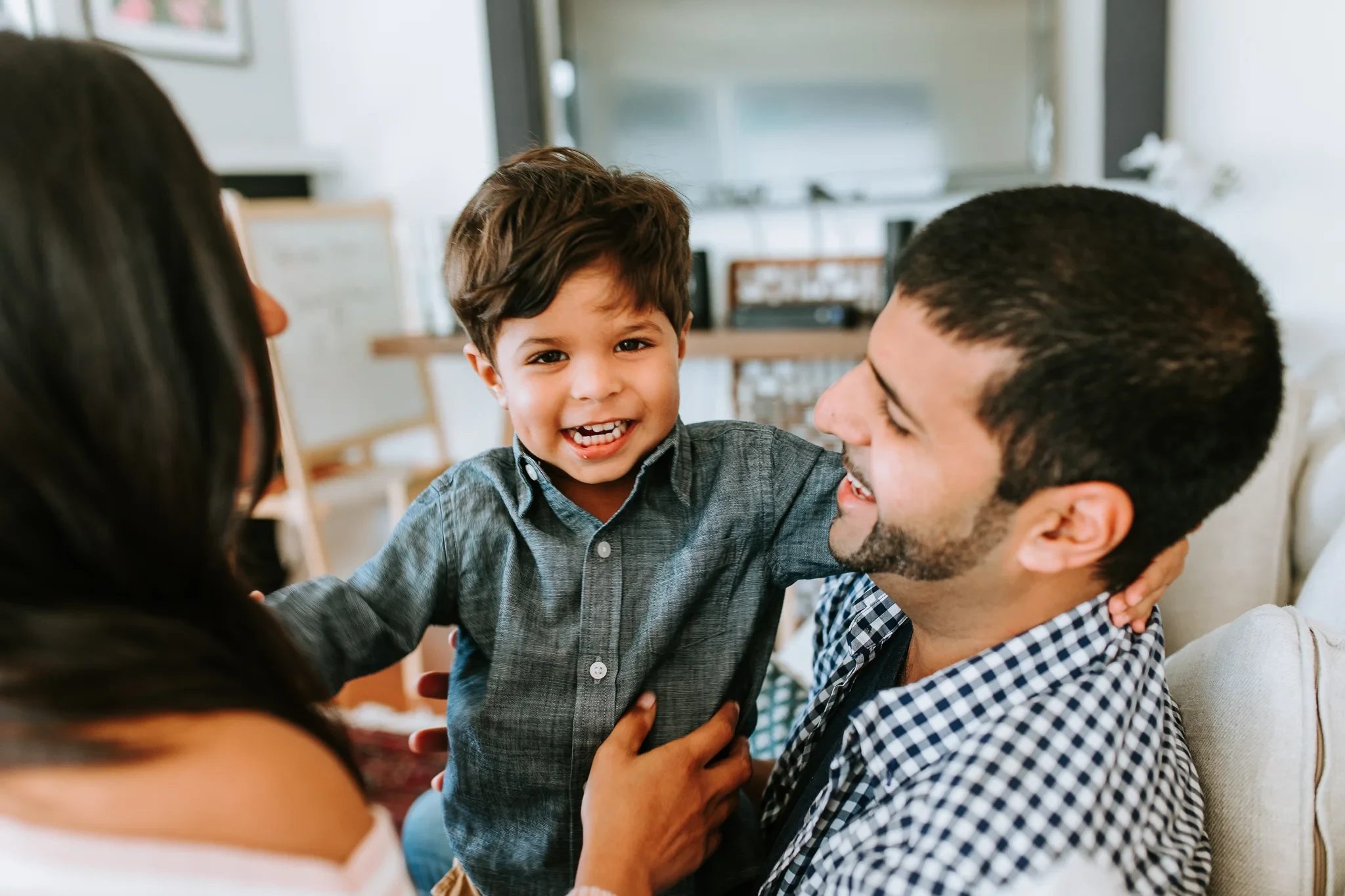 Smiling child leans into a man wearing a checked shirt