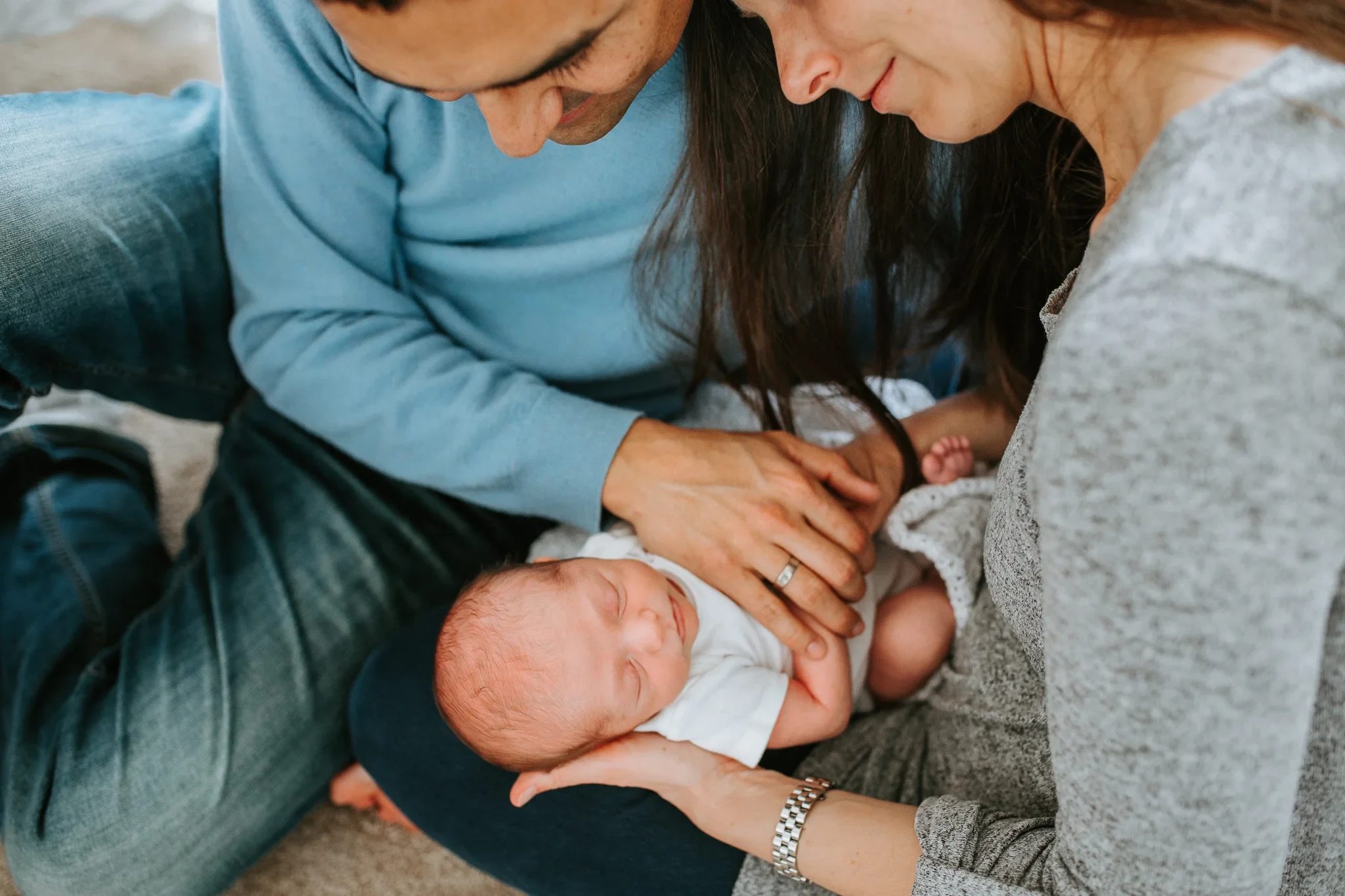 Close-up of adult hands gently touching a baby on a lap