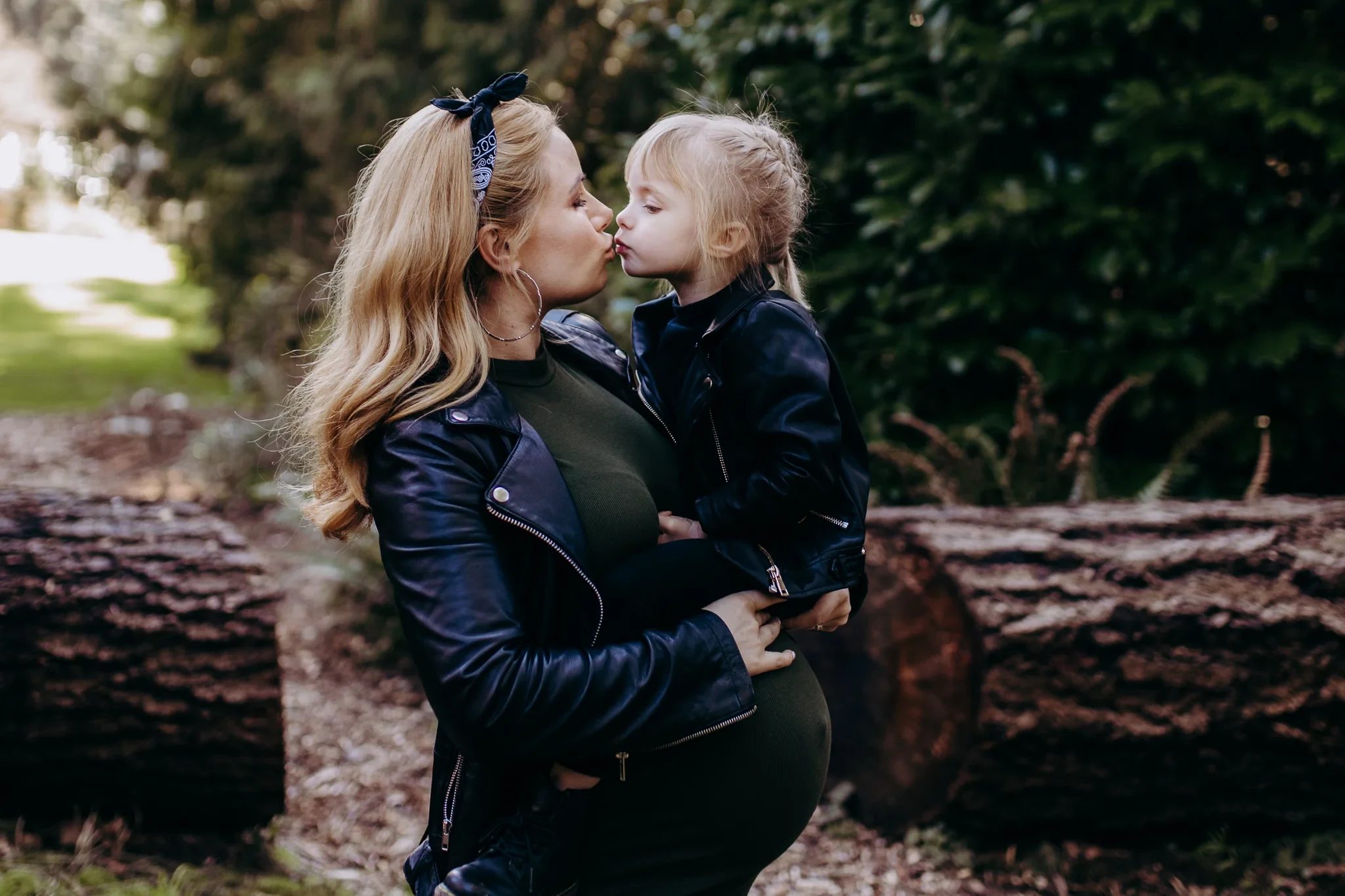 Woman and child touch noses beside a fallen tree
