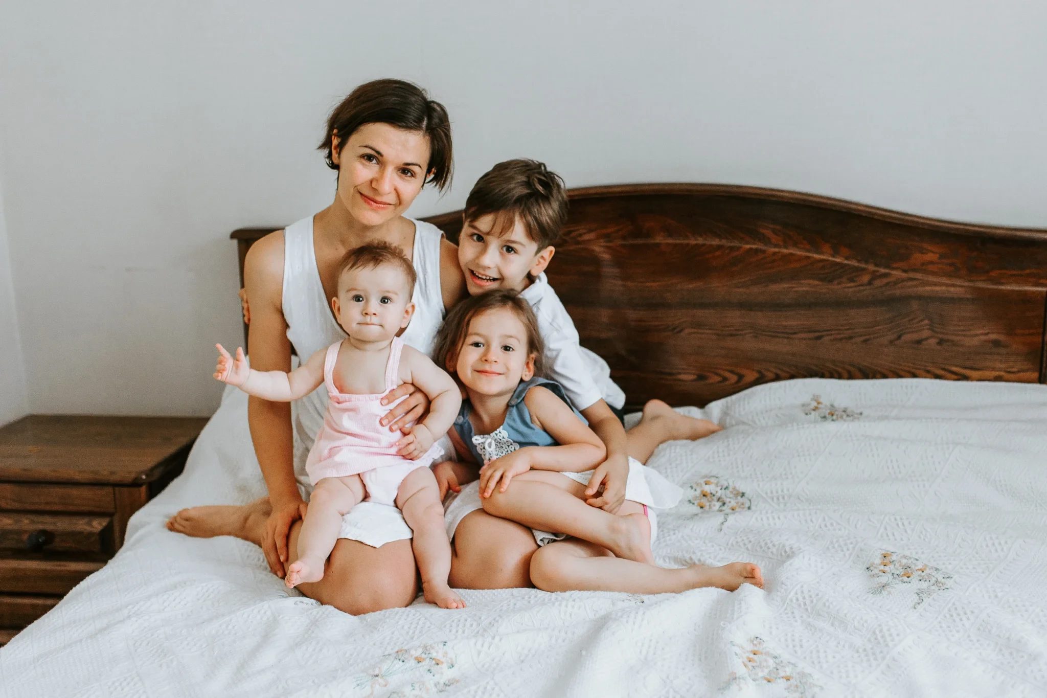 Woman and three children sit together on a bed