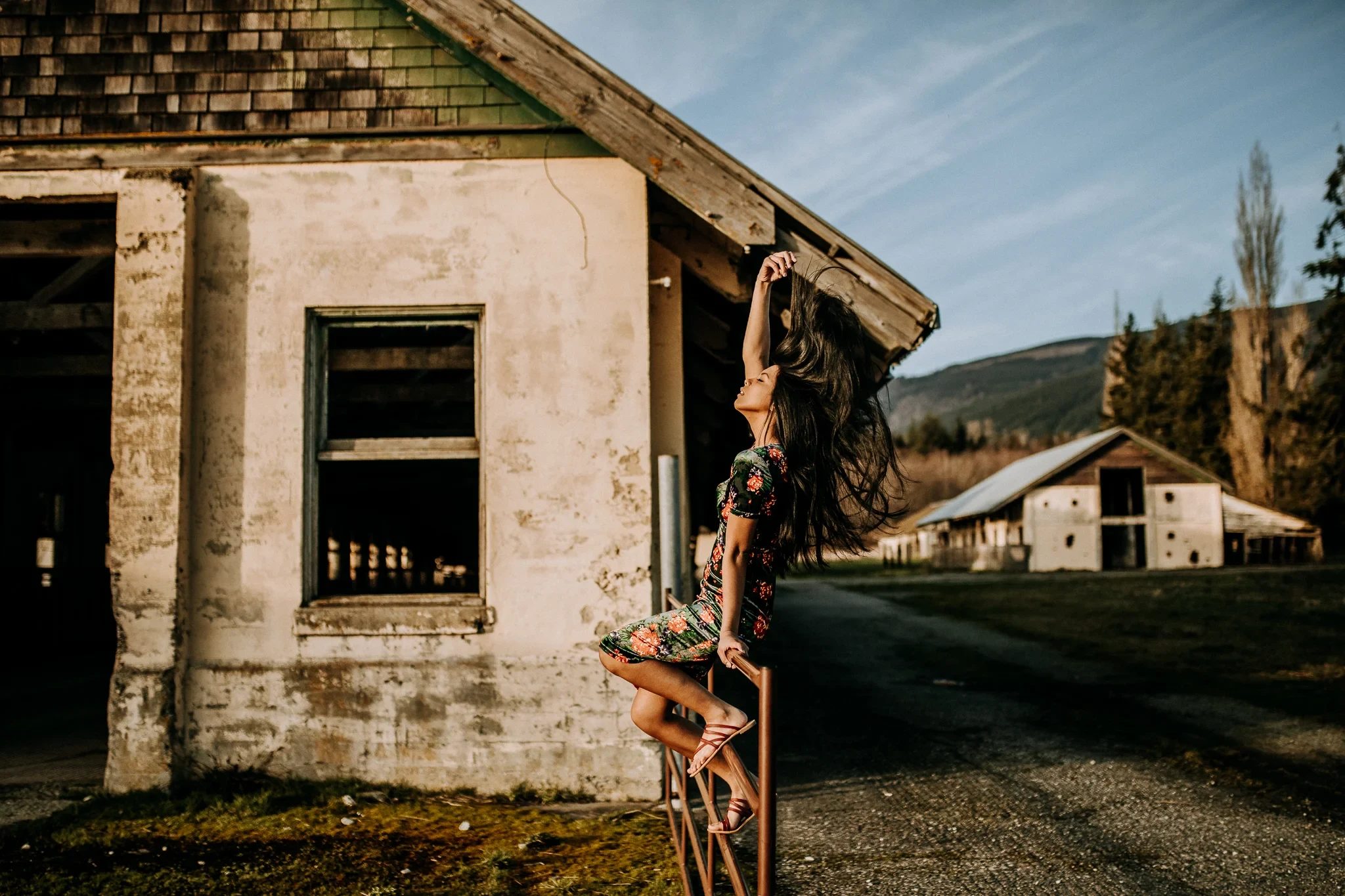 Woman poses against the corner of a weathered wooden building