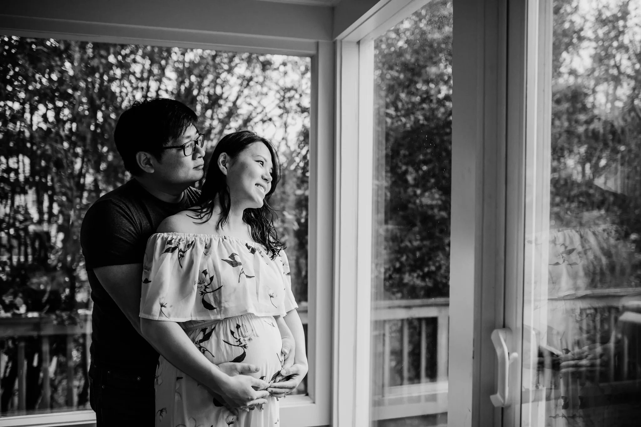 Black-and-white portrait of two adults standing by tall windows