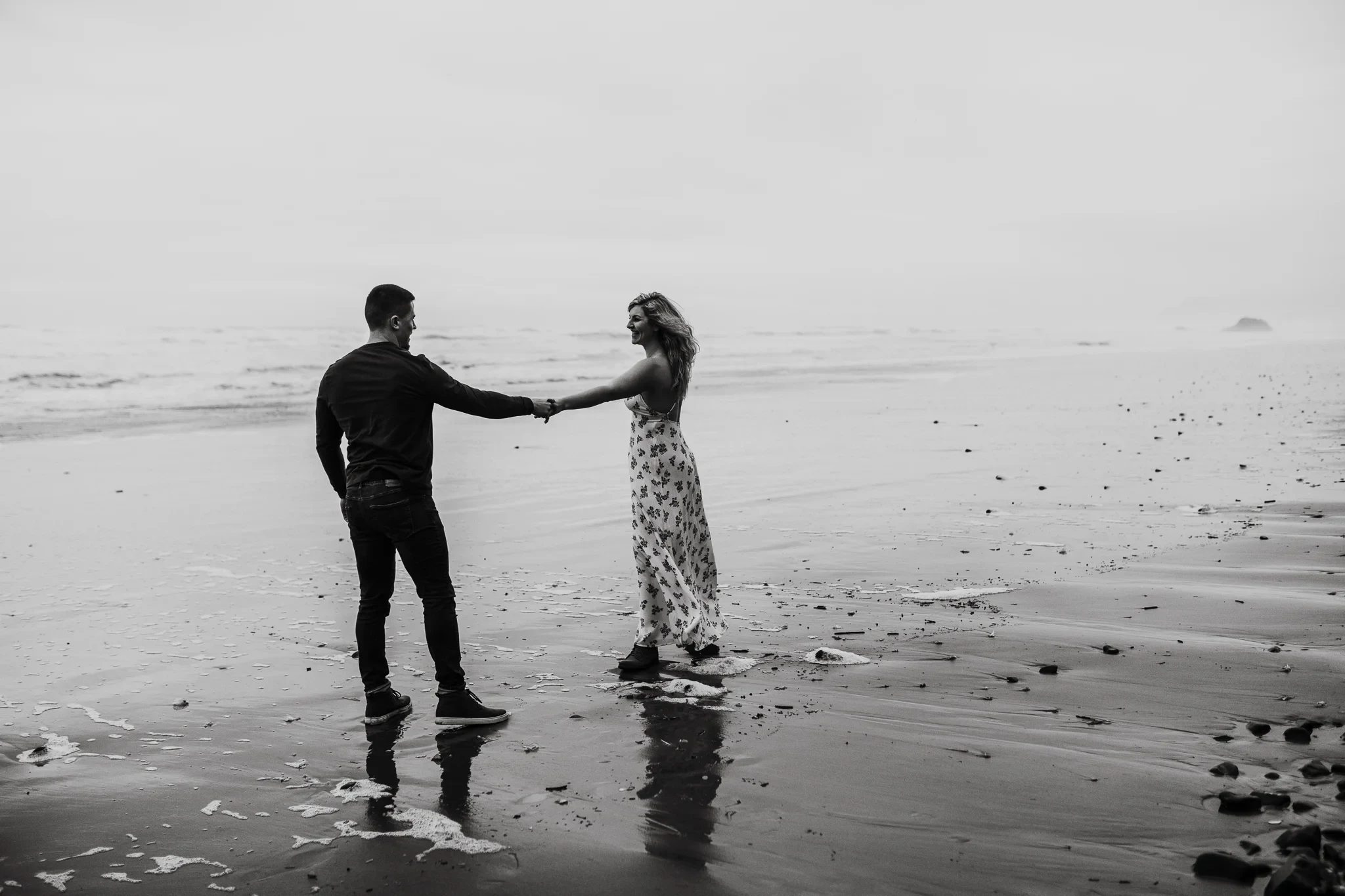 Black-and-white photograph of two adults holding hands at the water’s edge