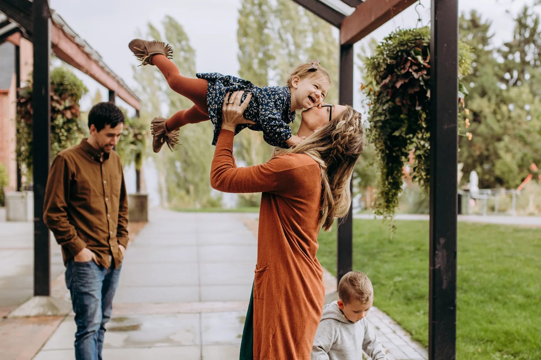 Woman lifts a child overhead beside a covered porch