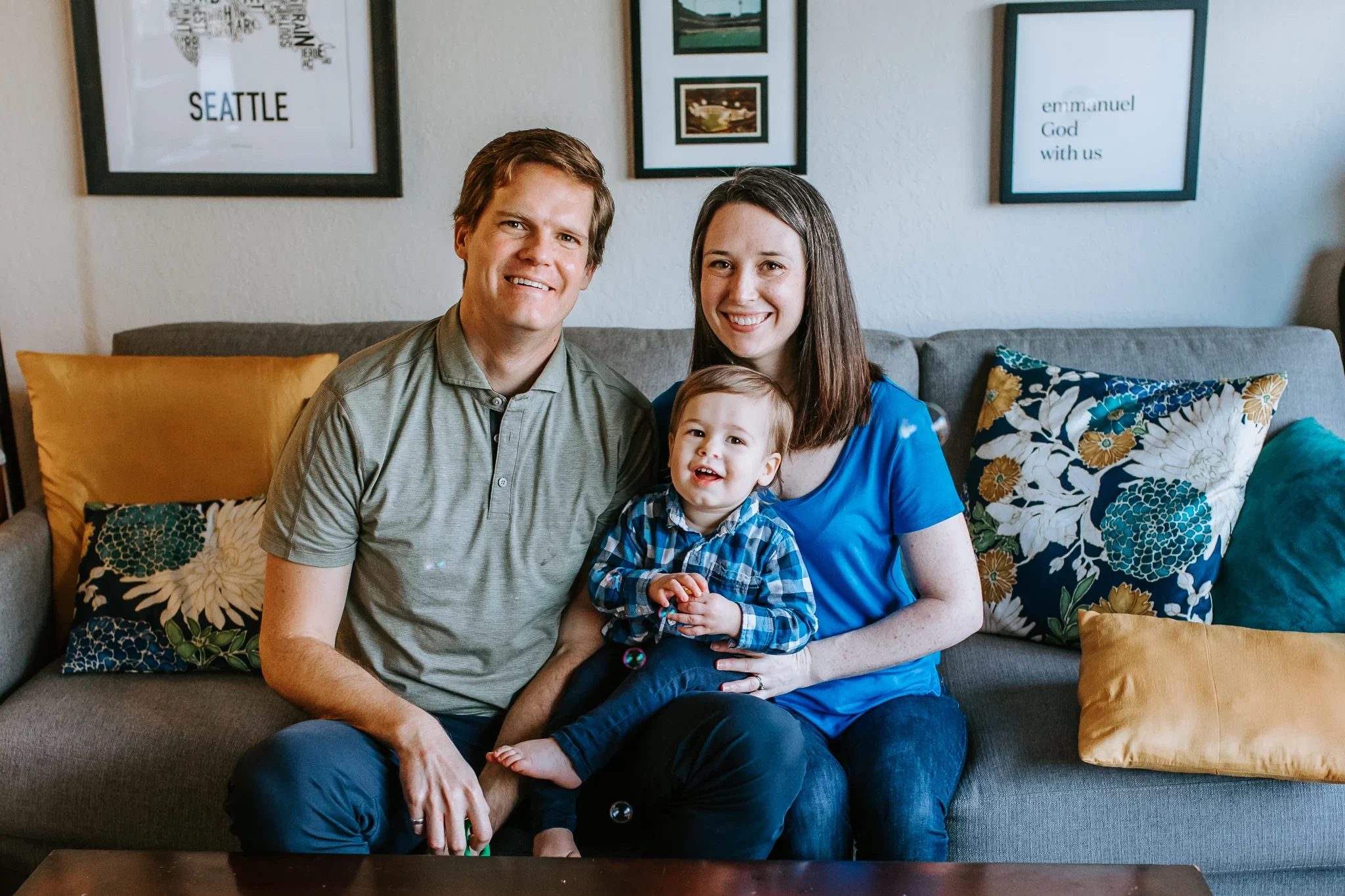 Family sits on a sofa below framed wall art