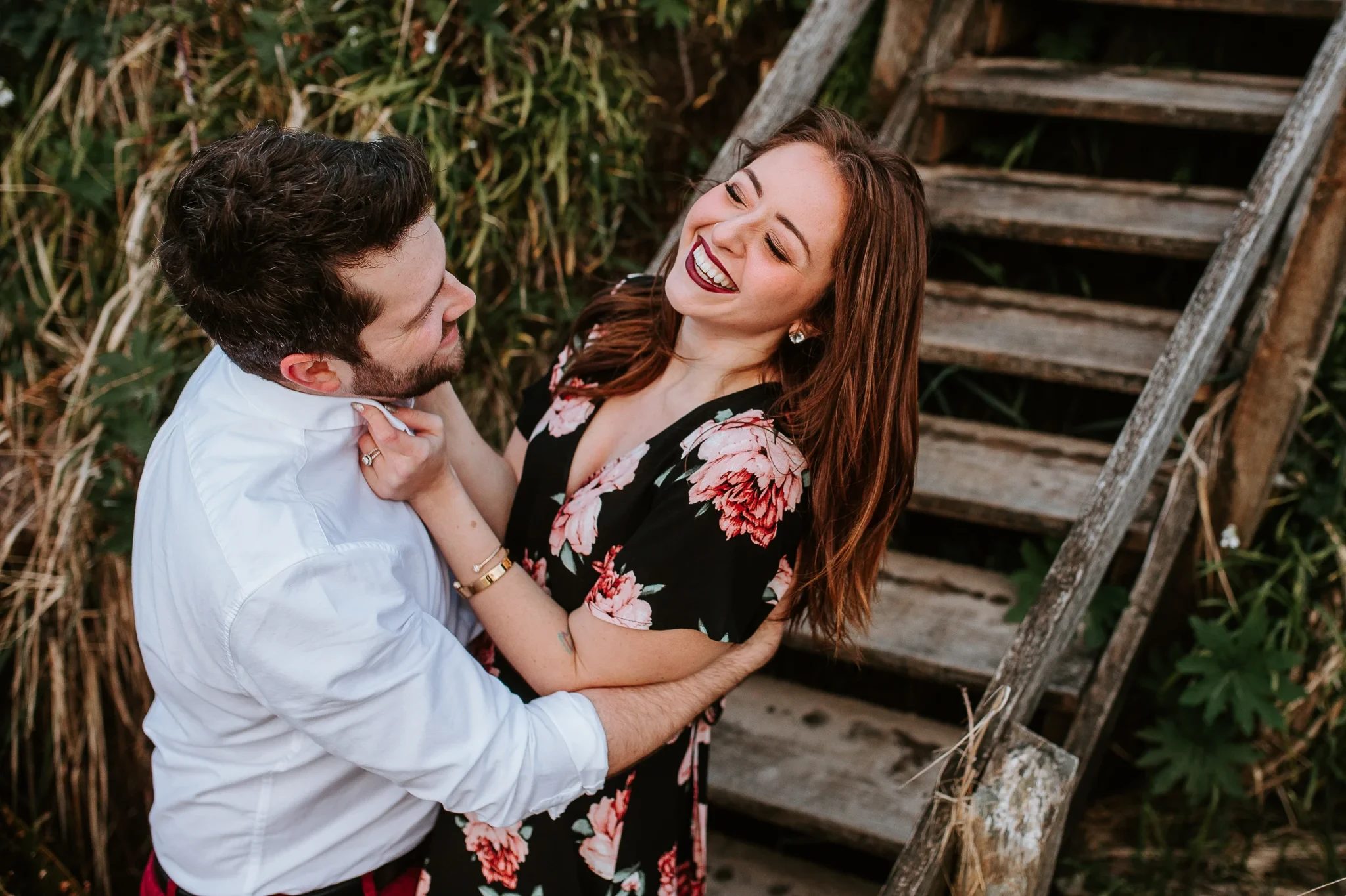 Two adults laugh together beside wooden outdoor steps