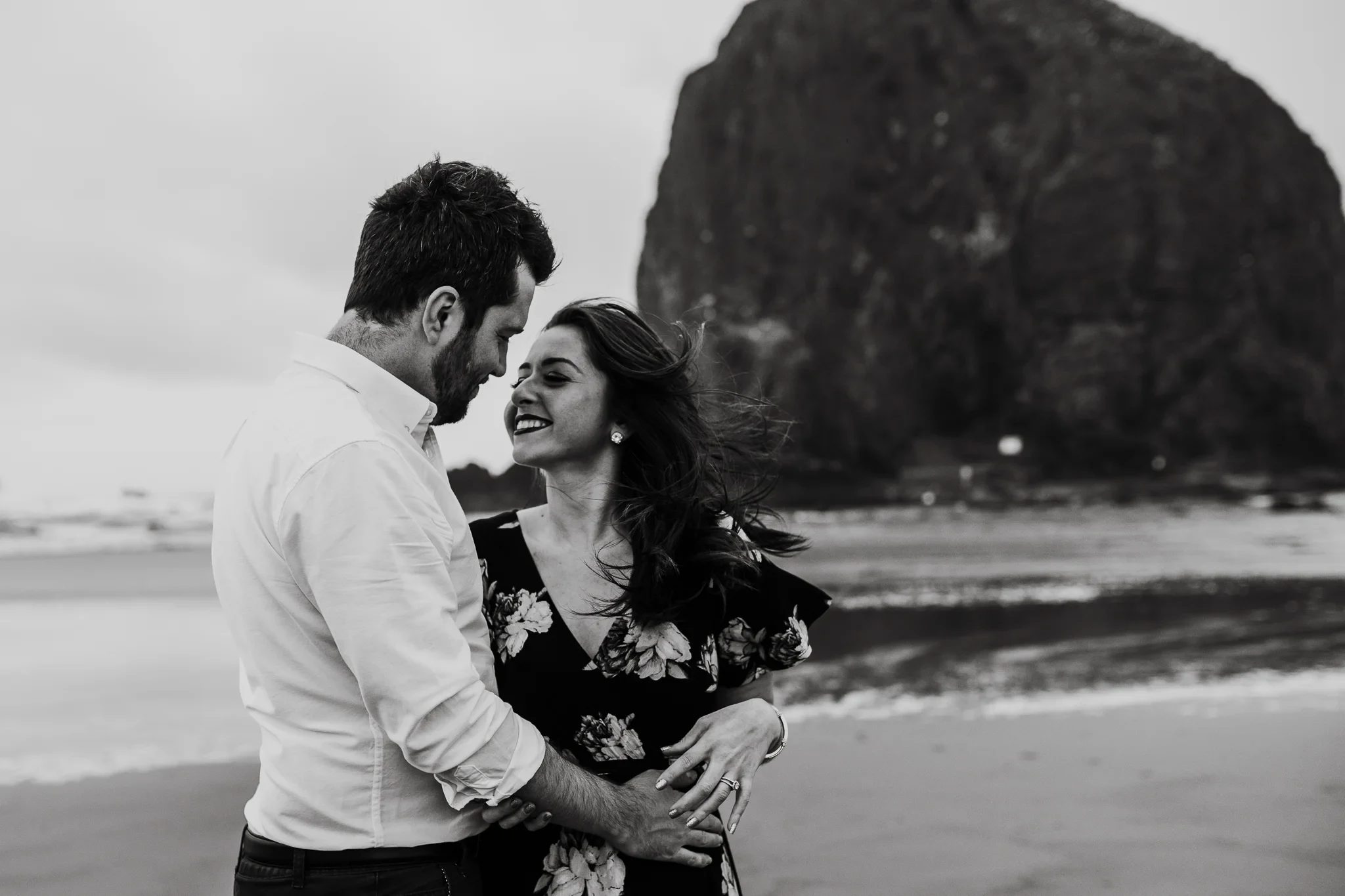 Black-and-white photograph of two adults smiling close together on a sandy beach