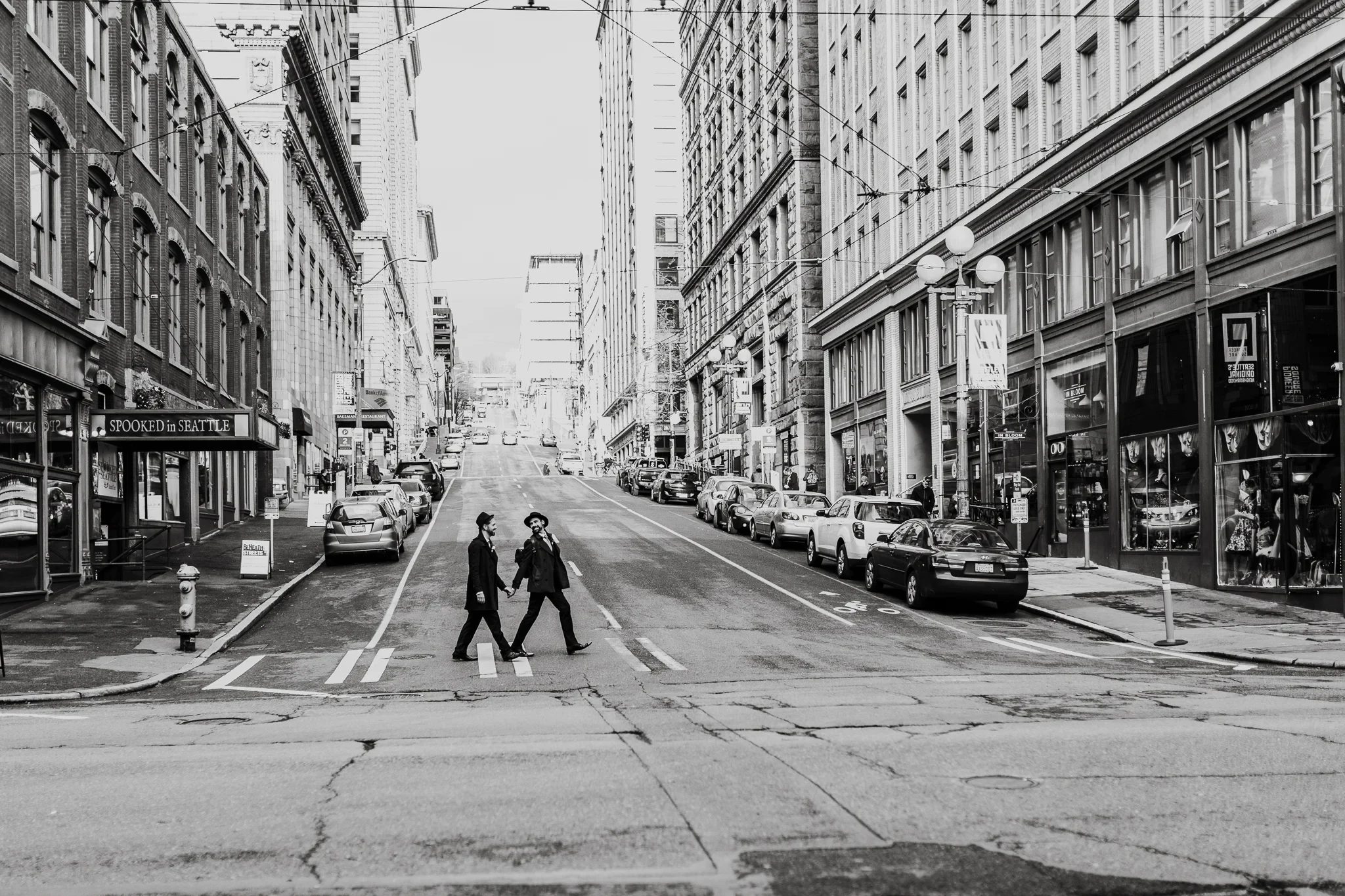 Black-and-white wide view of two people crossing a downtown street