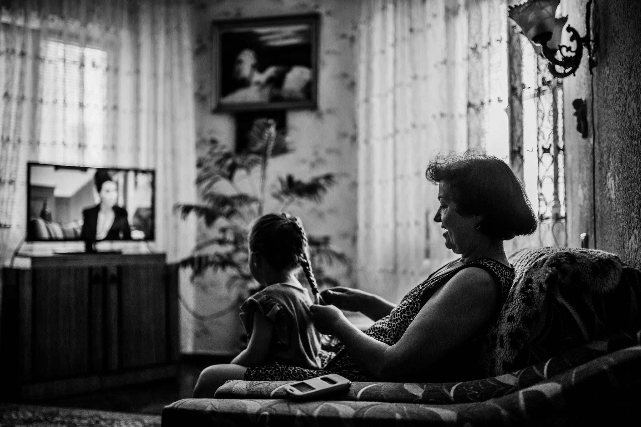 Black-and-white view of a woman and child relaxing beside a bright window