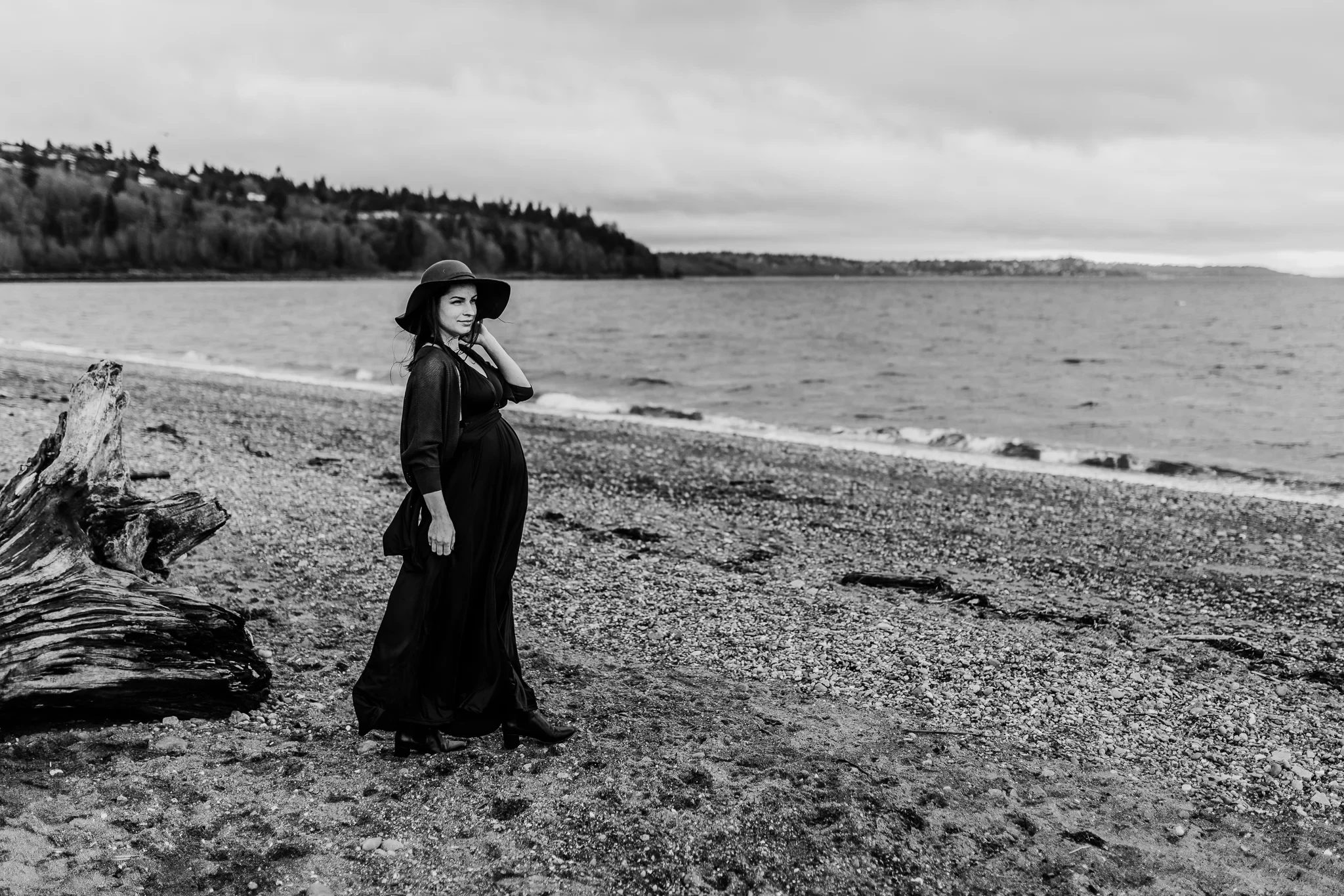 Black-and-white portrait of a woman in a long dress on a pebbled beach