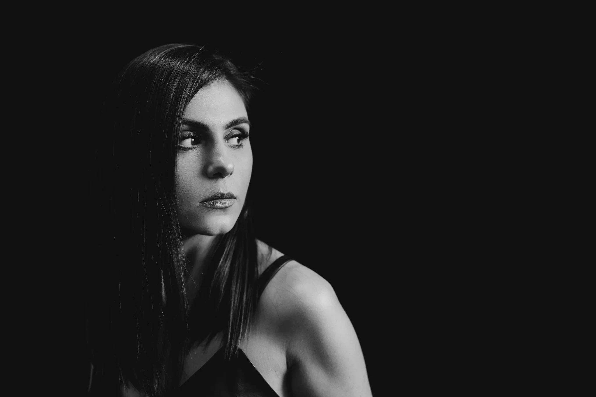 Black-and-white portrait of a woman looking to one side against a dark backdrop
