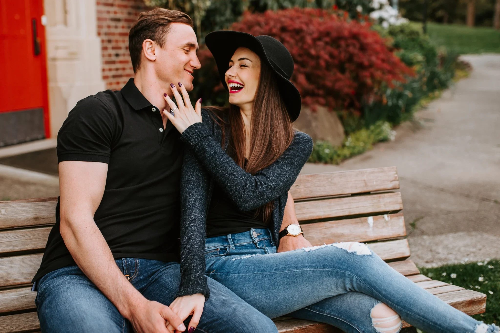Two adults laugh together on a wooden park bench