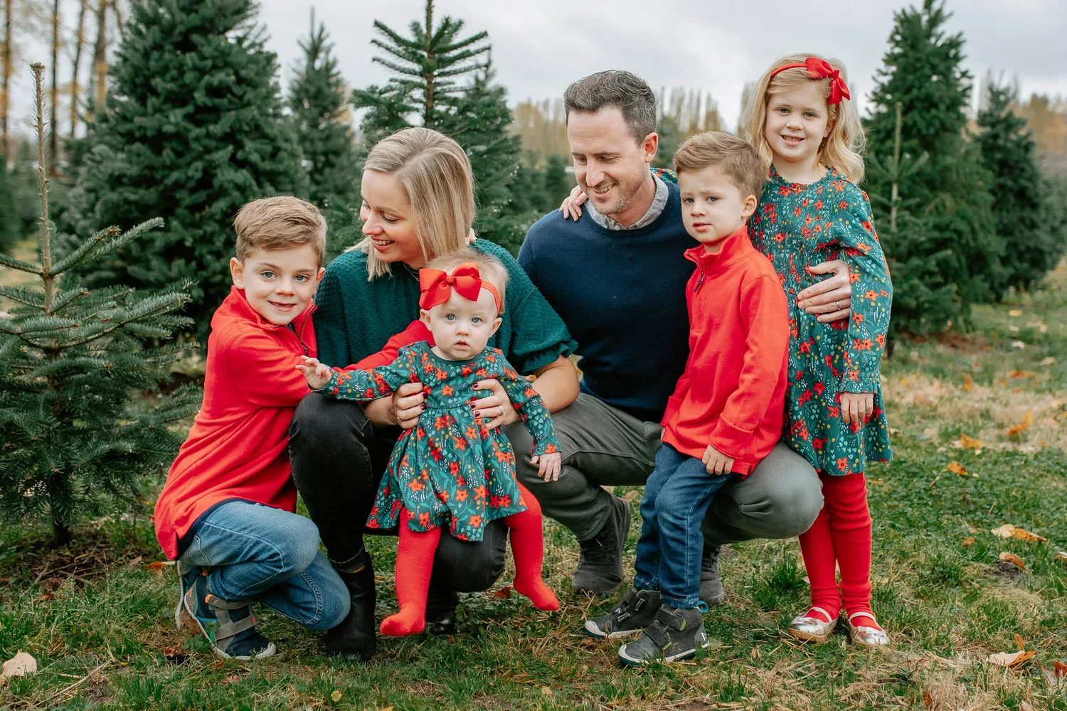 Family of five laughs together among Christmas trees