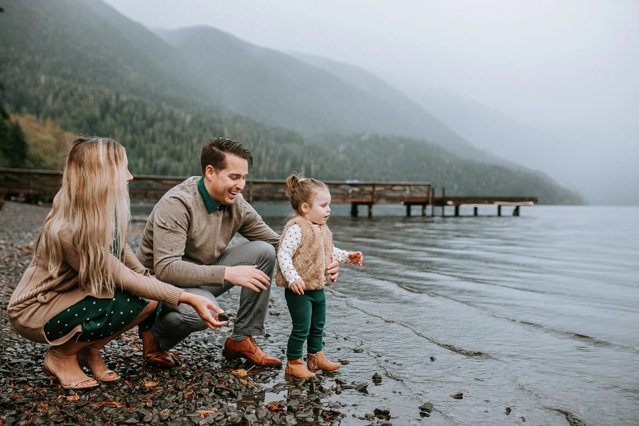 Family sharing a playful moment on a misty lakeshore