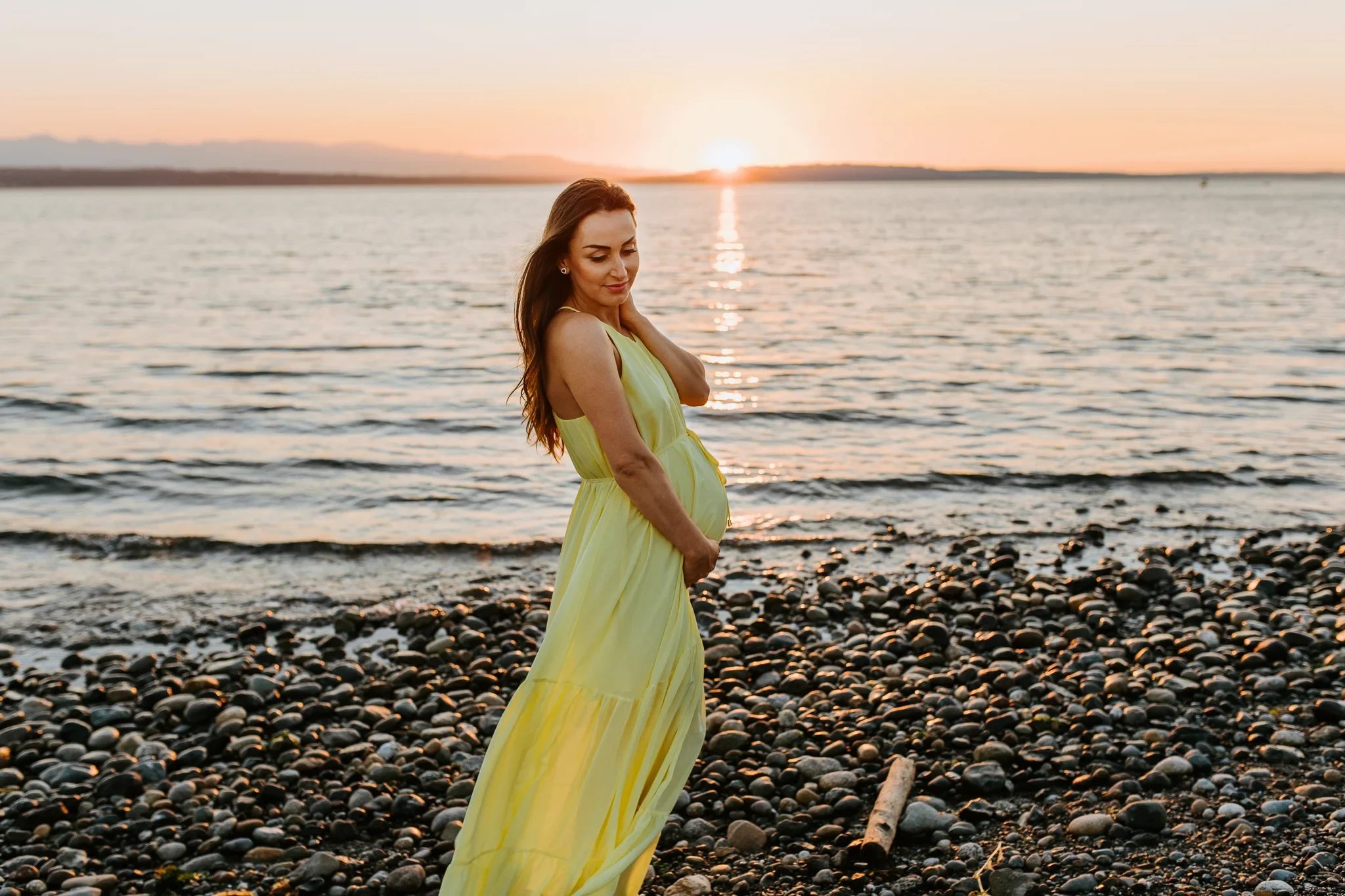Woman in a flowing yellow dress turns toward the setting sun