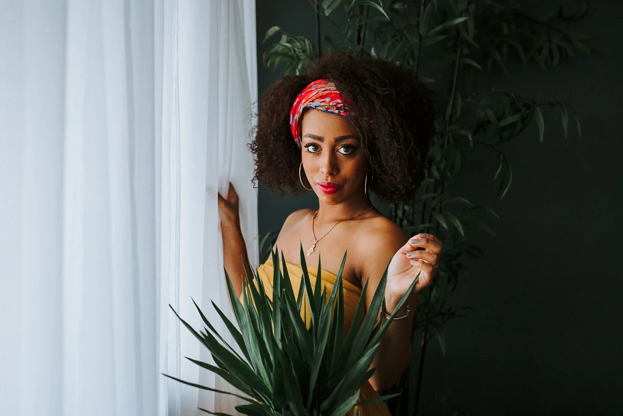 Woman posing beside a window among indoor plants