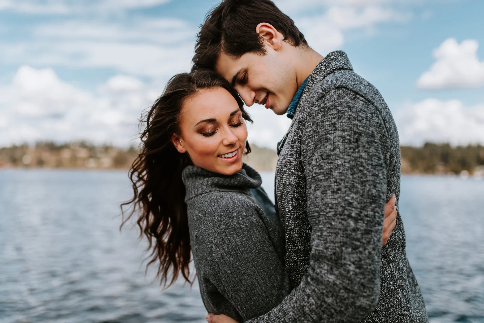 Two adults hold one another close beside water
