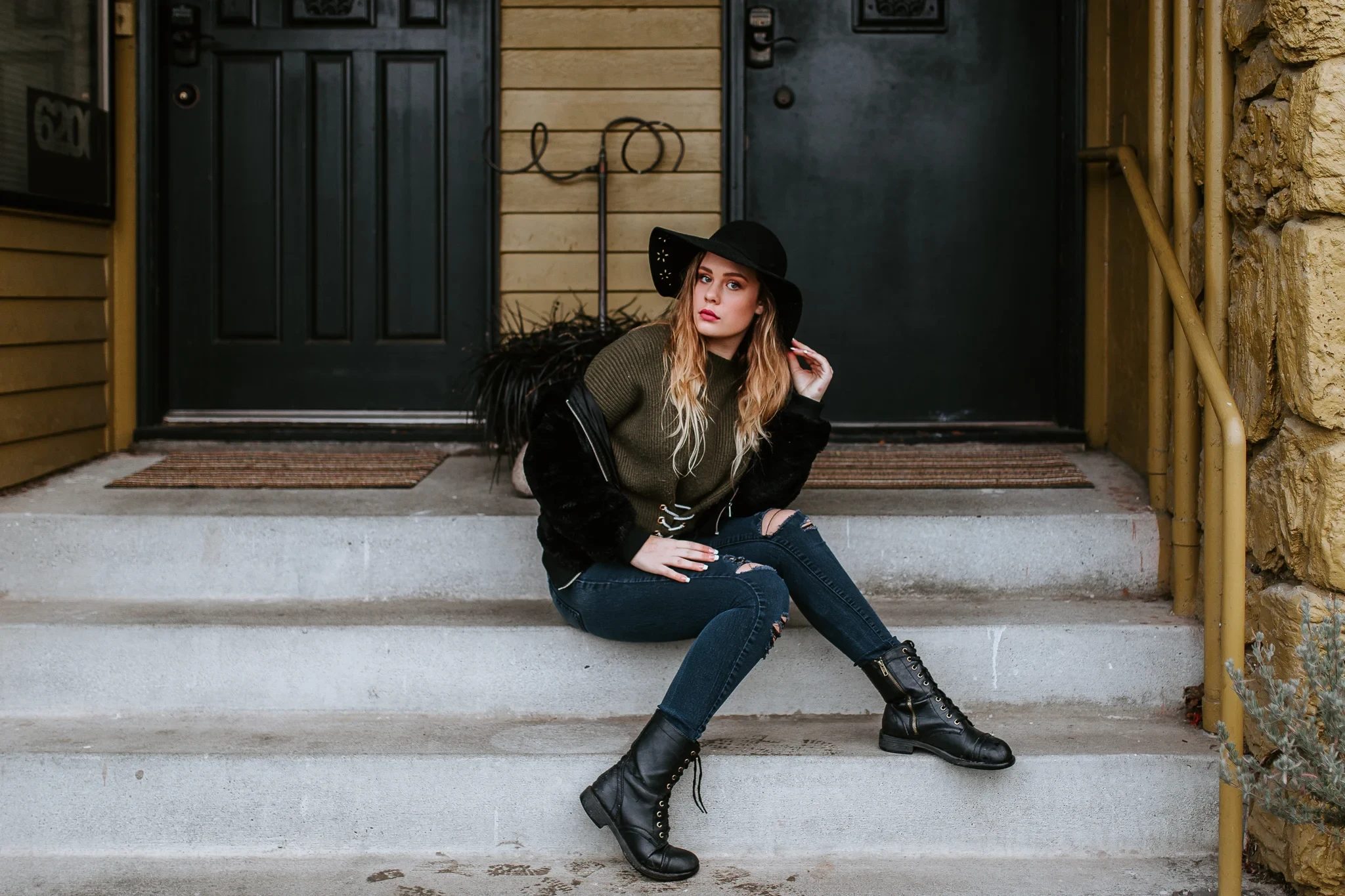 Woman in dark clothing sits on stone steps beside a doorway