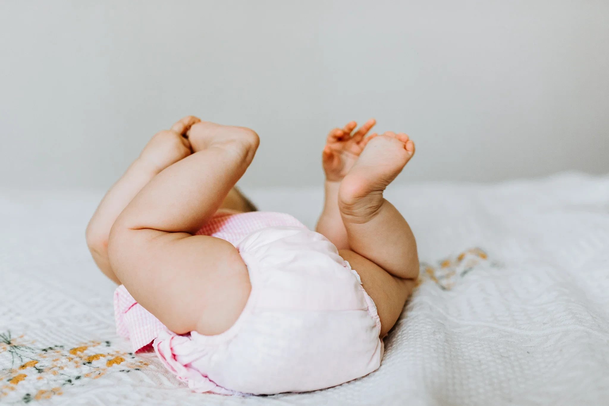 Close-up of a baby’s raised feet against pale bedding