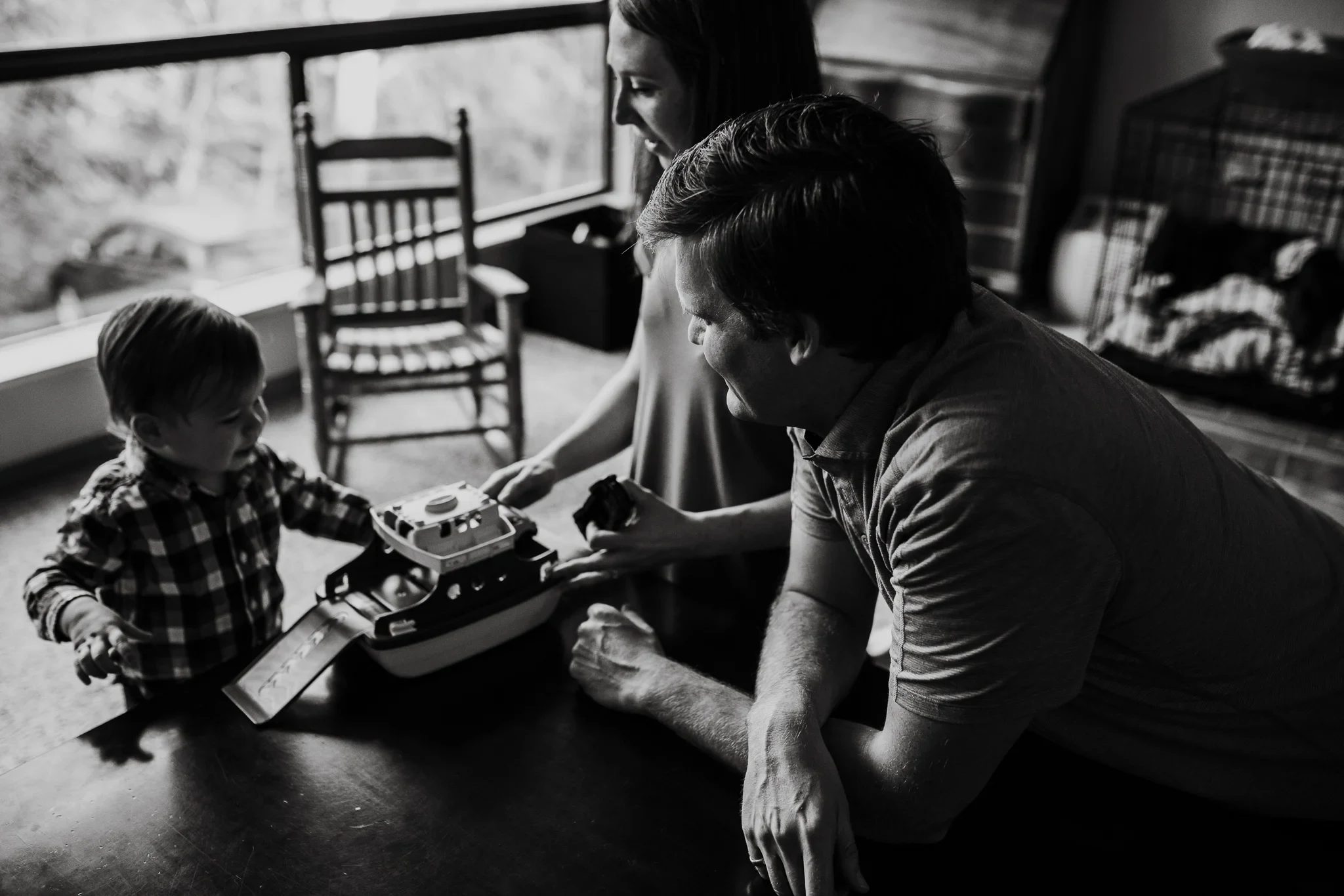Black-and-white photograph of a man and child playing guitar by a window