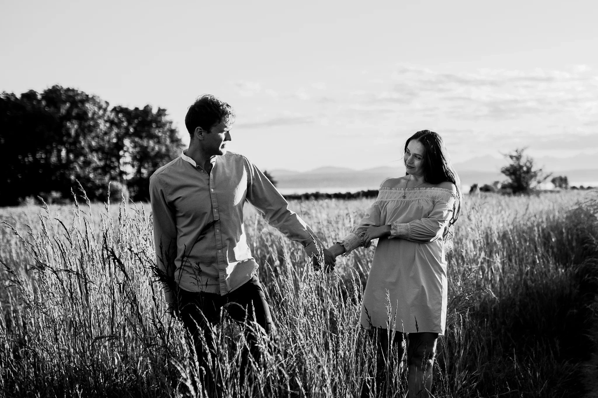 Black-and-white photograph of two adults holding hands in a meadow