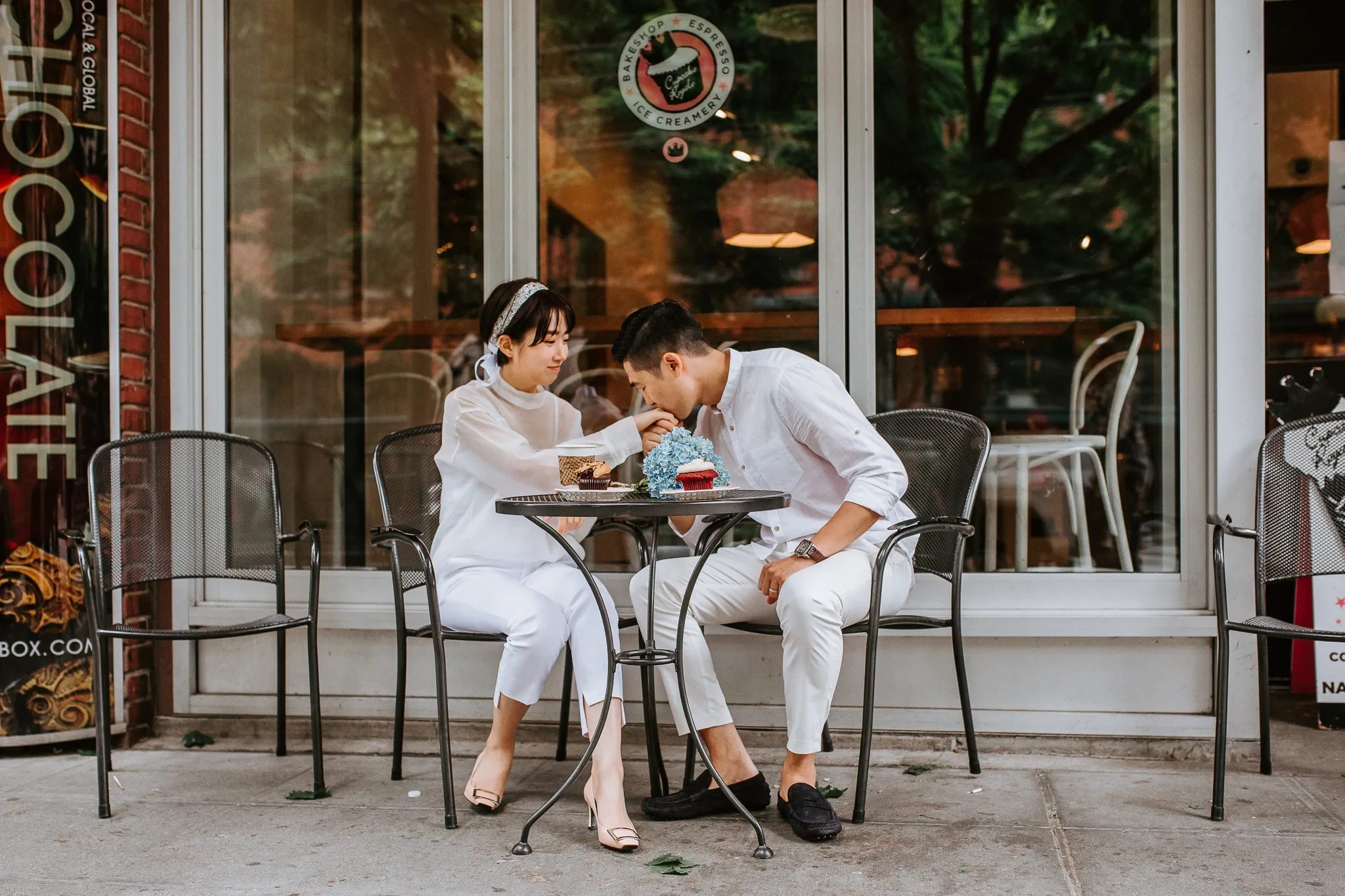 Two adults sit at a small outdoor café table