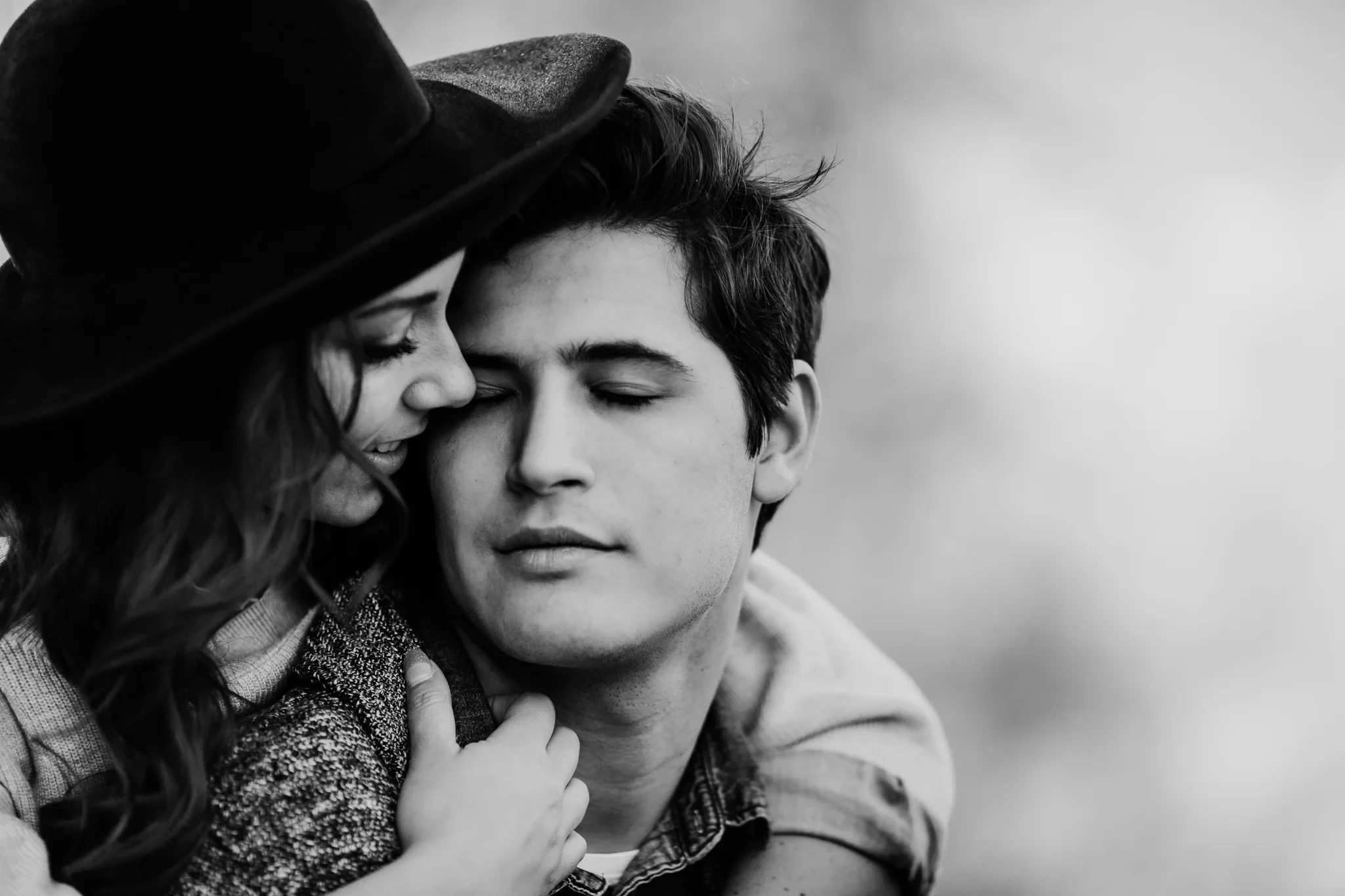 Black-and-white close-up of two adults leaning cheek to cheek