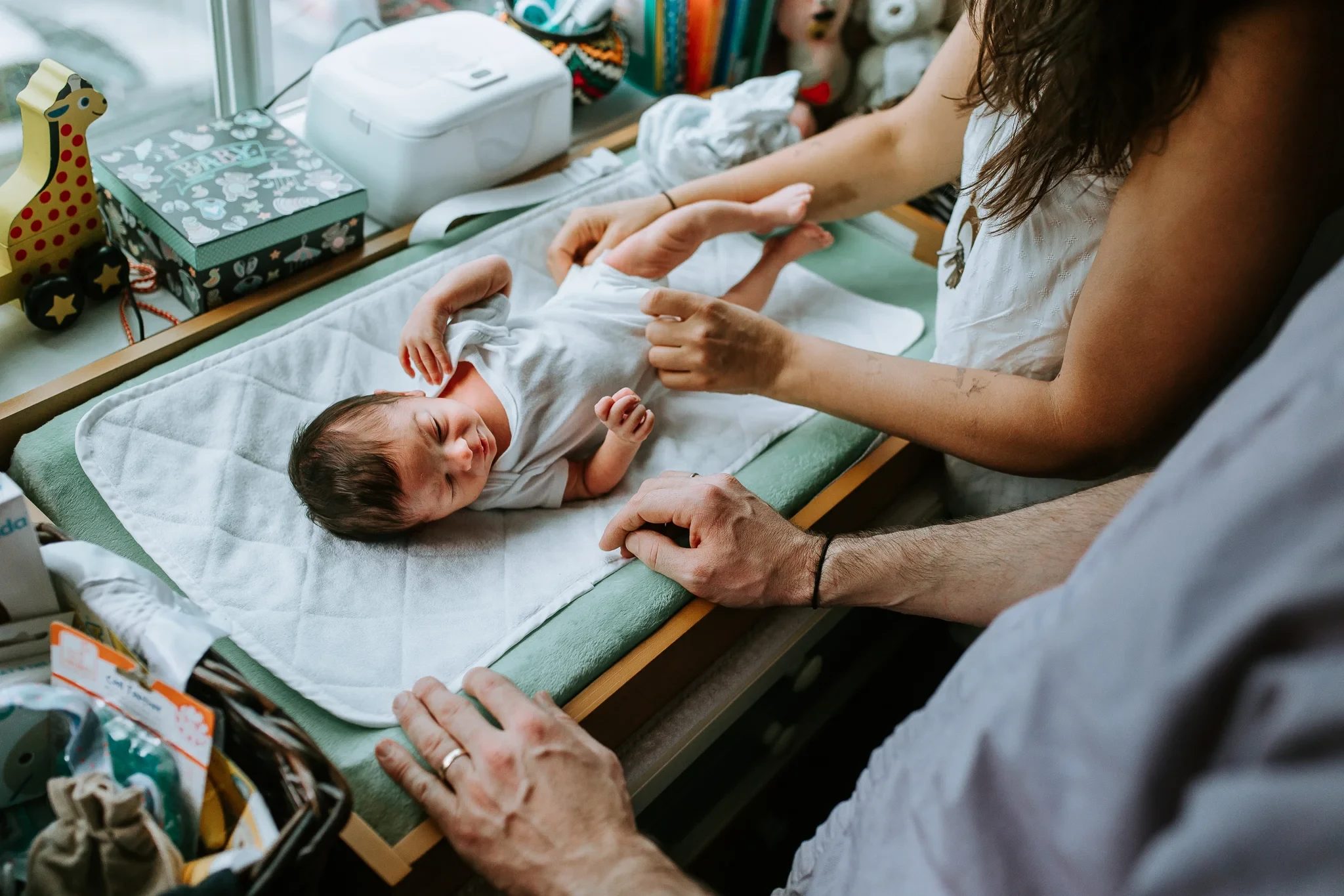 Adult hands care for a baby lying on a changing table