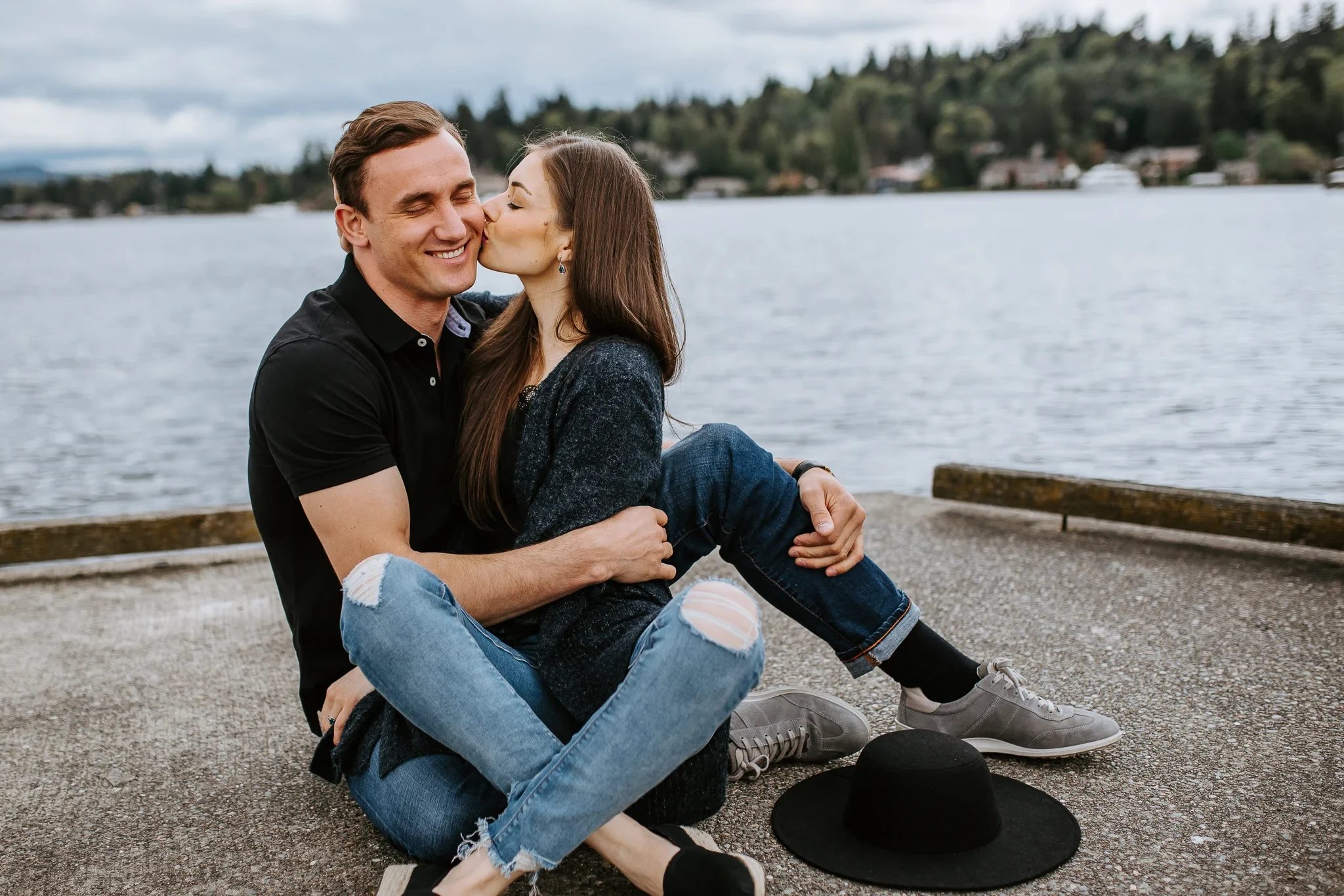 Two adults sit together on a waterfront ledge