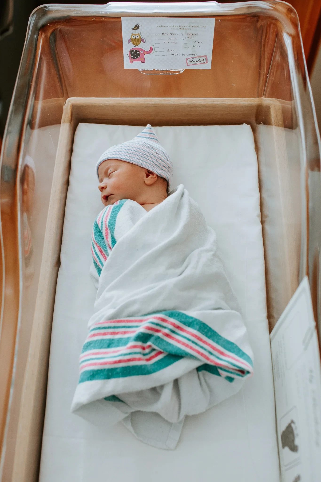 Overhead view of a swaddled baby in a clear hospital bassinet
