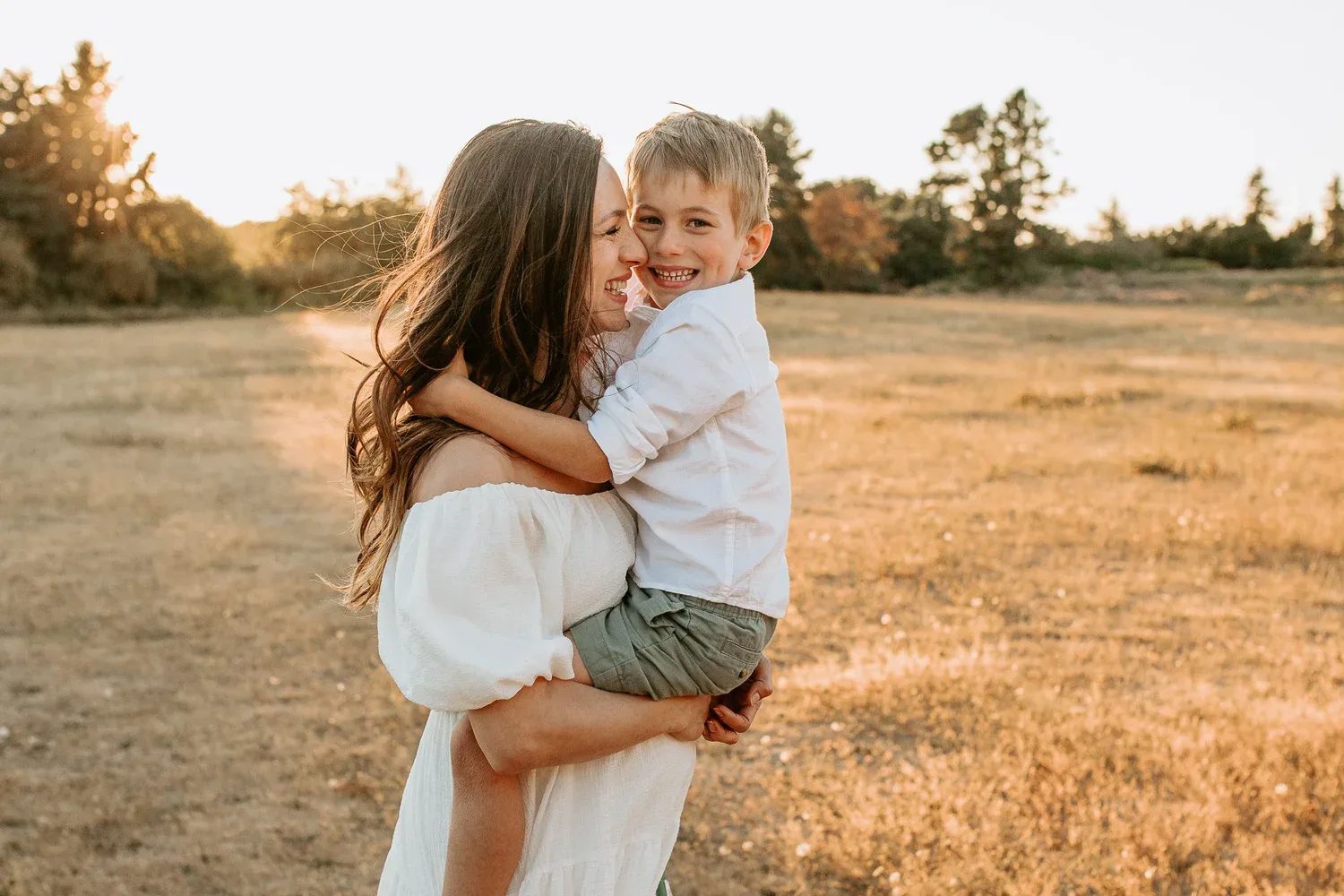 Woman carrying a smiling child in a sunlit meadow