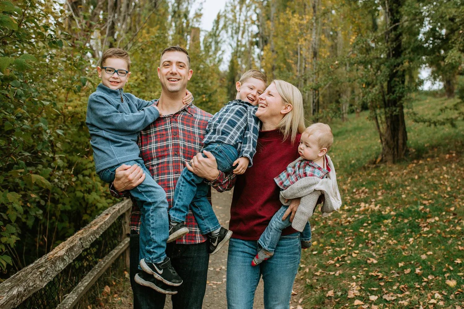 Family of five stands beside a rustic wooden fence