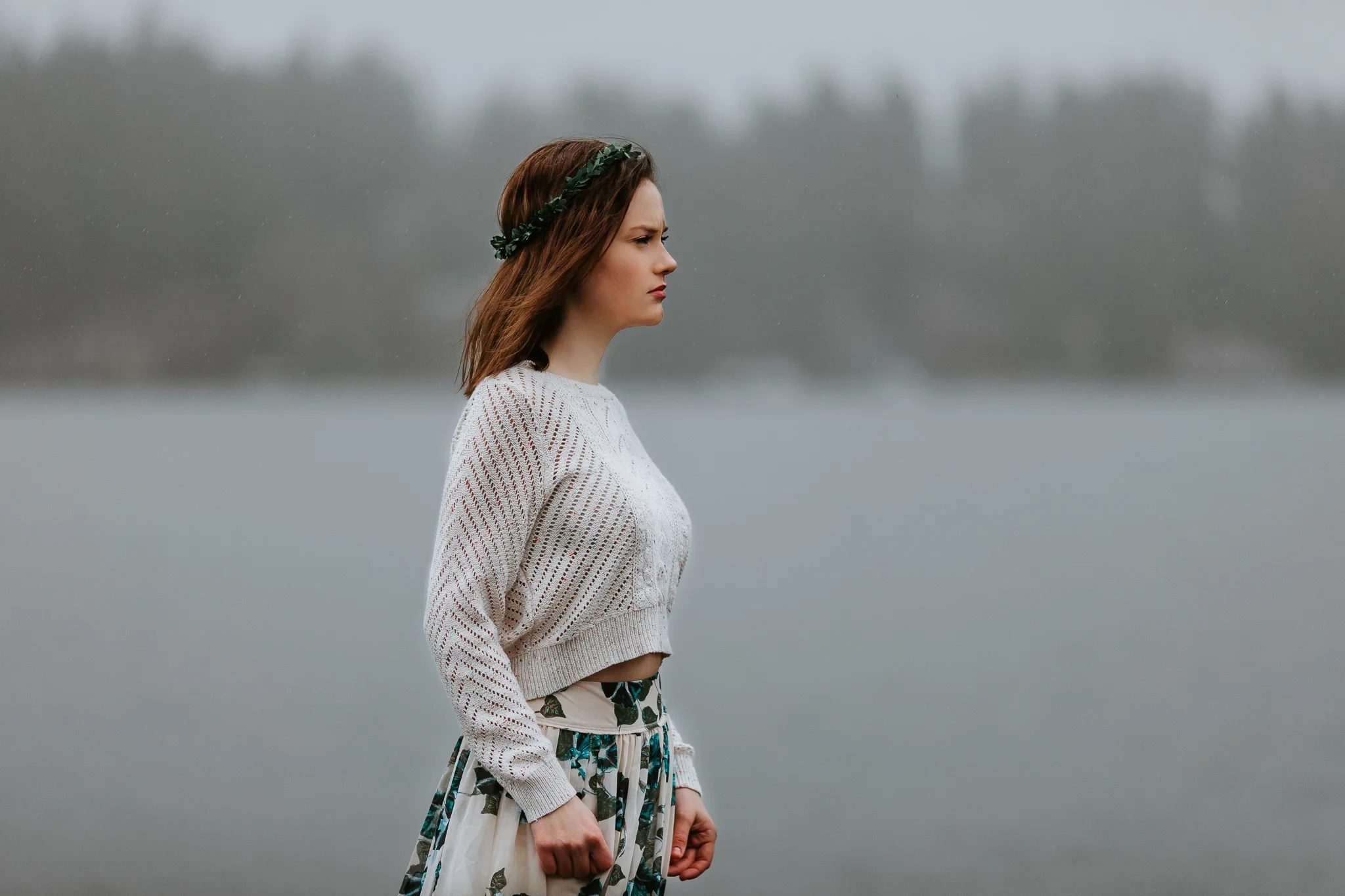 Woman in a pale sweater looks across misty water
